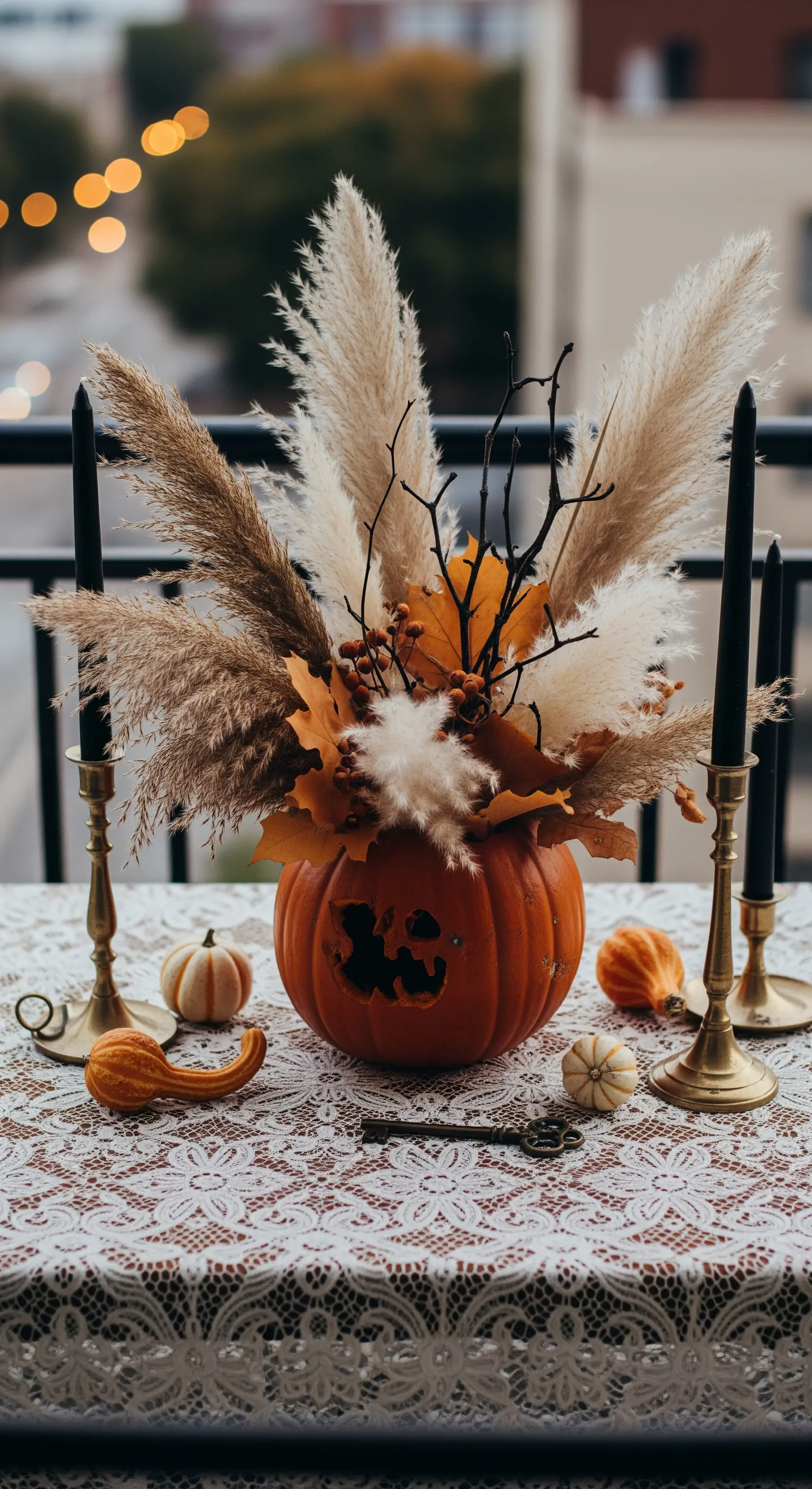 Balkontisch mit Kürbis-Centerpiece, Pampasgras, schwarzen Kerzen und Spitzendecke