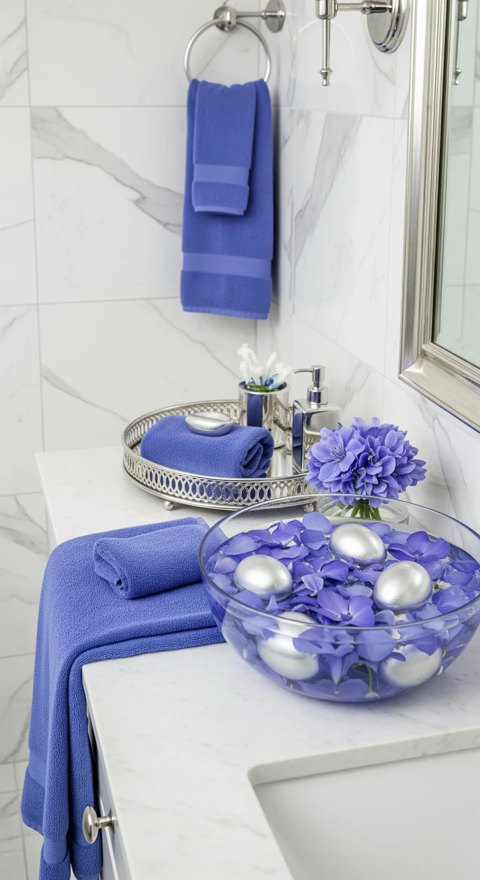 Badezimmer mit blauen Handtüchern, blauen Hortensien und silbernen Eiern in einer Schale.