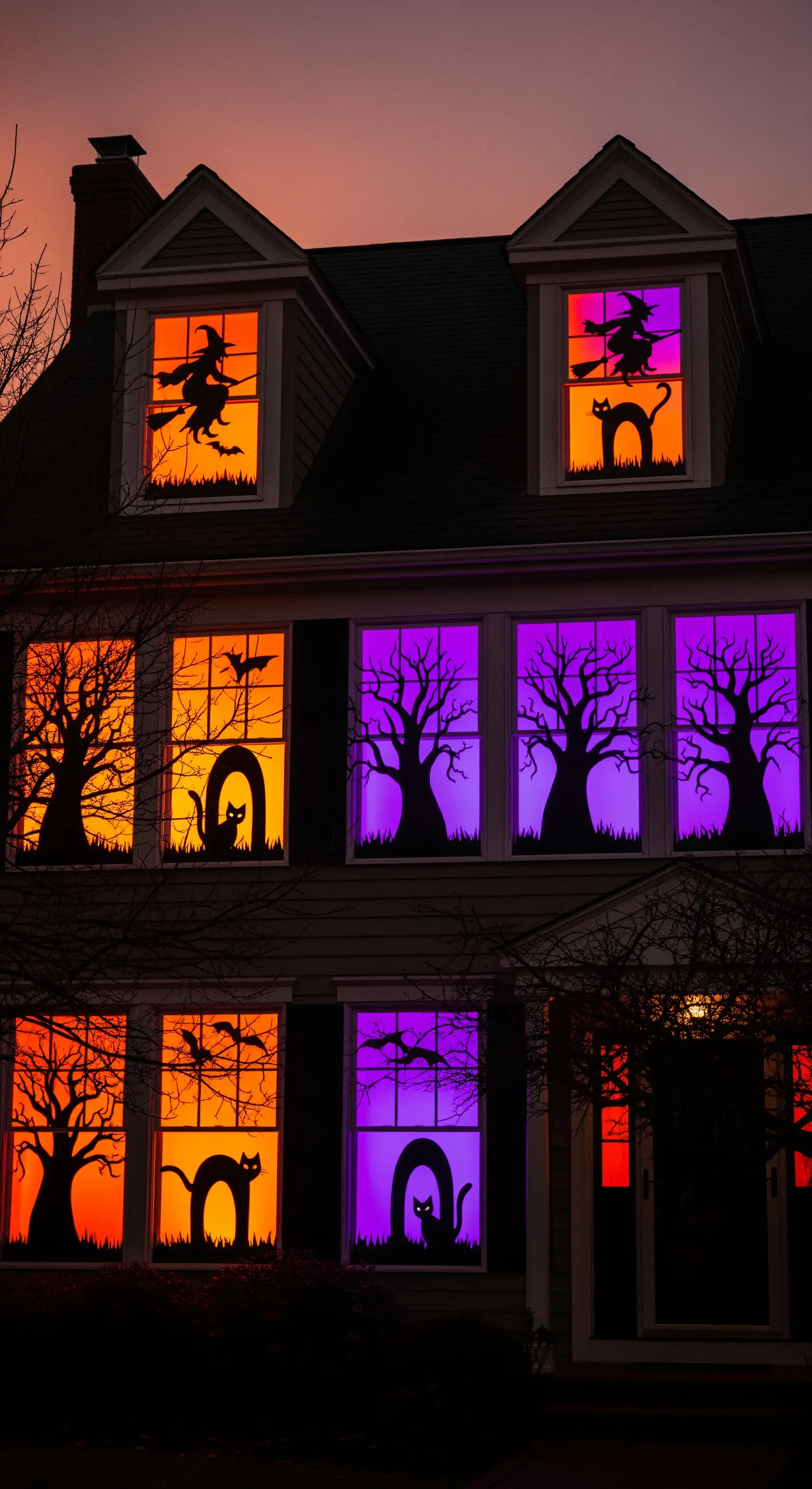 Halloween Fensterbeleuchtung mit orangen und violetten Lichtern, schwarzen Silhouetten.