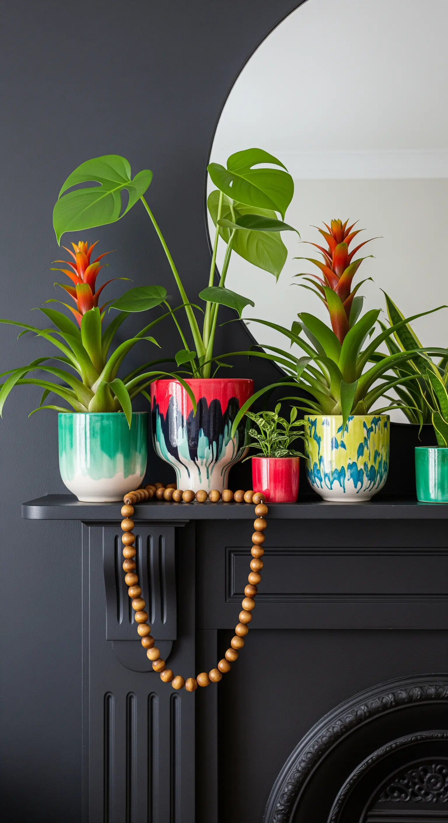 Bunte, bemalte Blumentöpfe mit exotischen Pflanzen auf einem schwarz gestrichenen Kaminsims