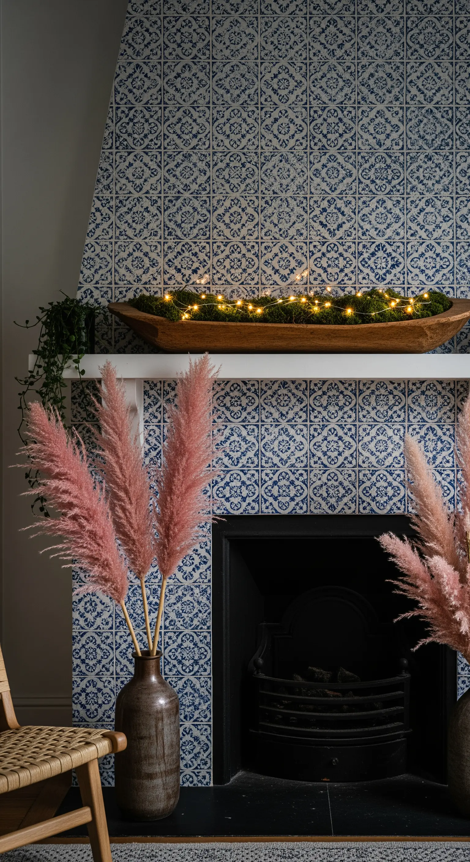 Kamin mit blauen Kacheln, rosa Pampasgras und Moosschale