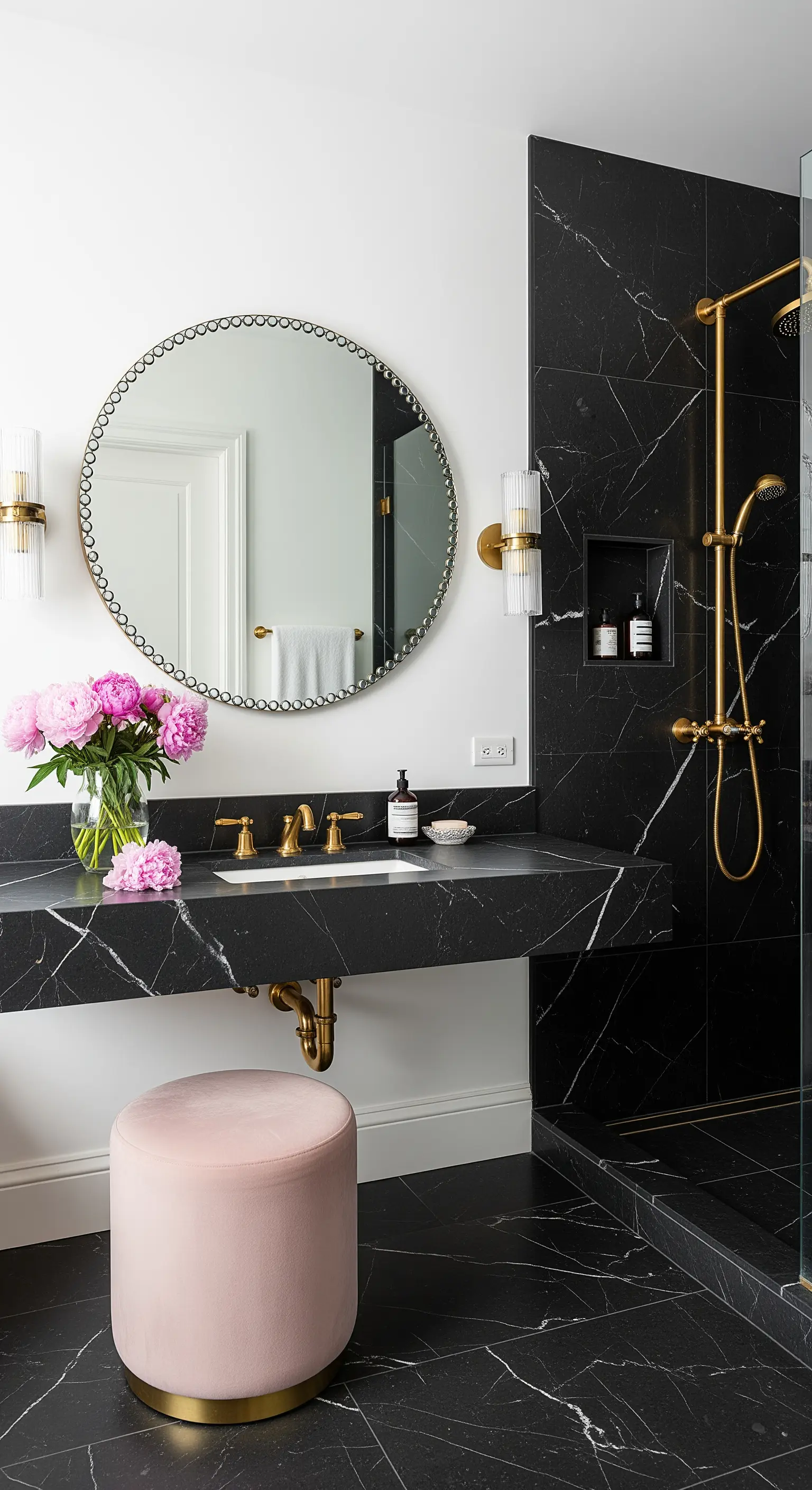 Schwarzes Marmorbad mit einem rosa Samthocker und einem Strauss rosa Pfingstrosen.