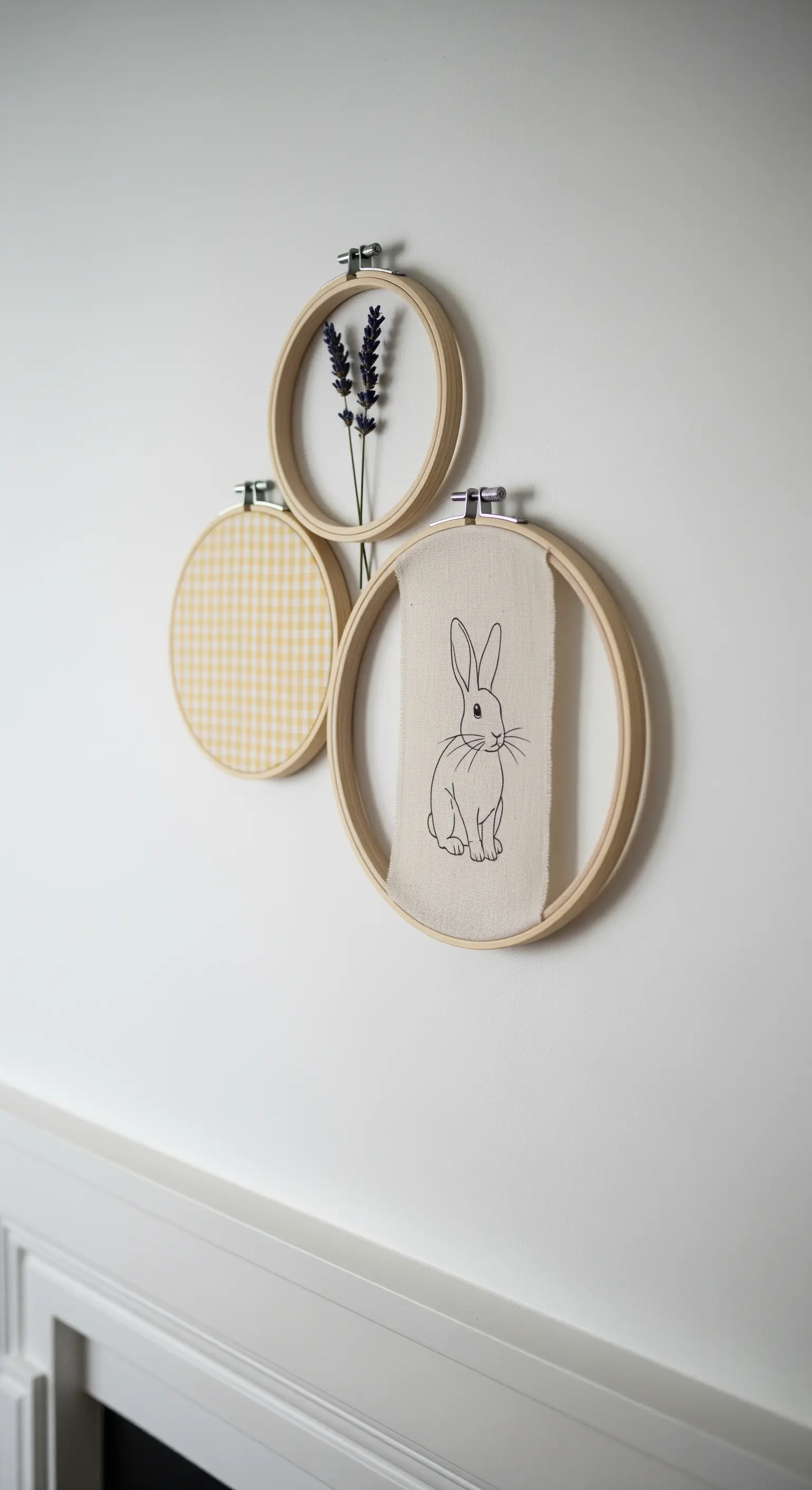 Drei Stickrahmen mit Stoff, einer Hasenzeichnung und Lavendel als Wanddeko.