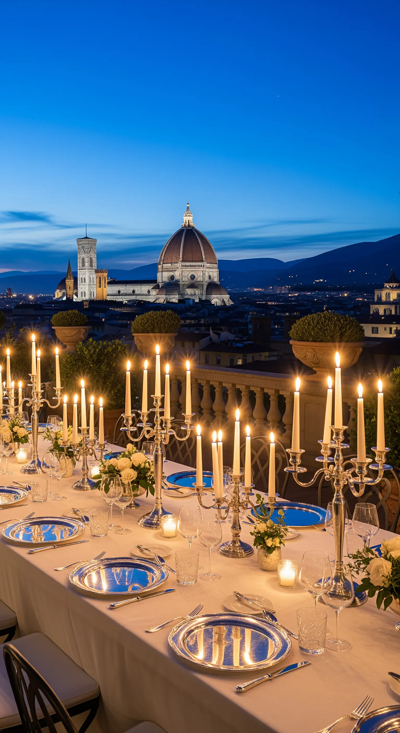 Langer Tisch mit weißen Tischdecken, silbernen Kerzenleuchtern und weißen Blumen vor Florenz-Panorama.