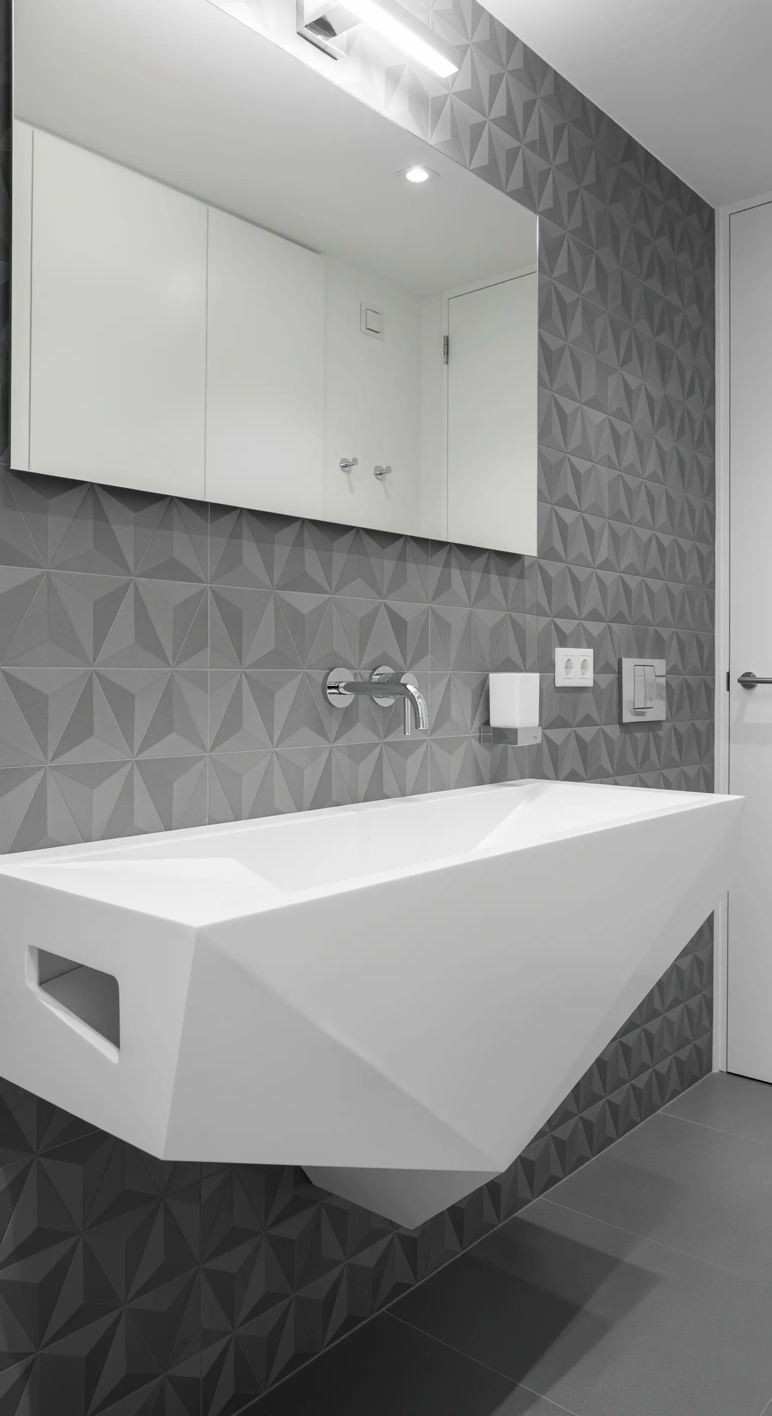 Weißes, facettiertes und schwebendes Waschbecken vor einer grauen 3D-Fliesenwand.
