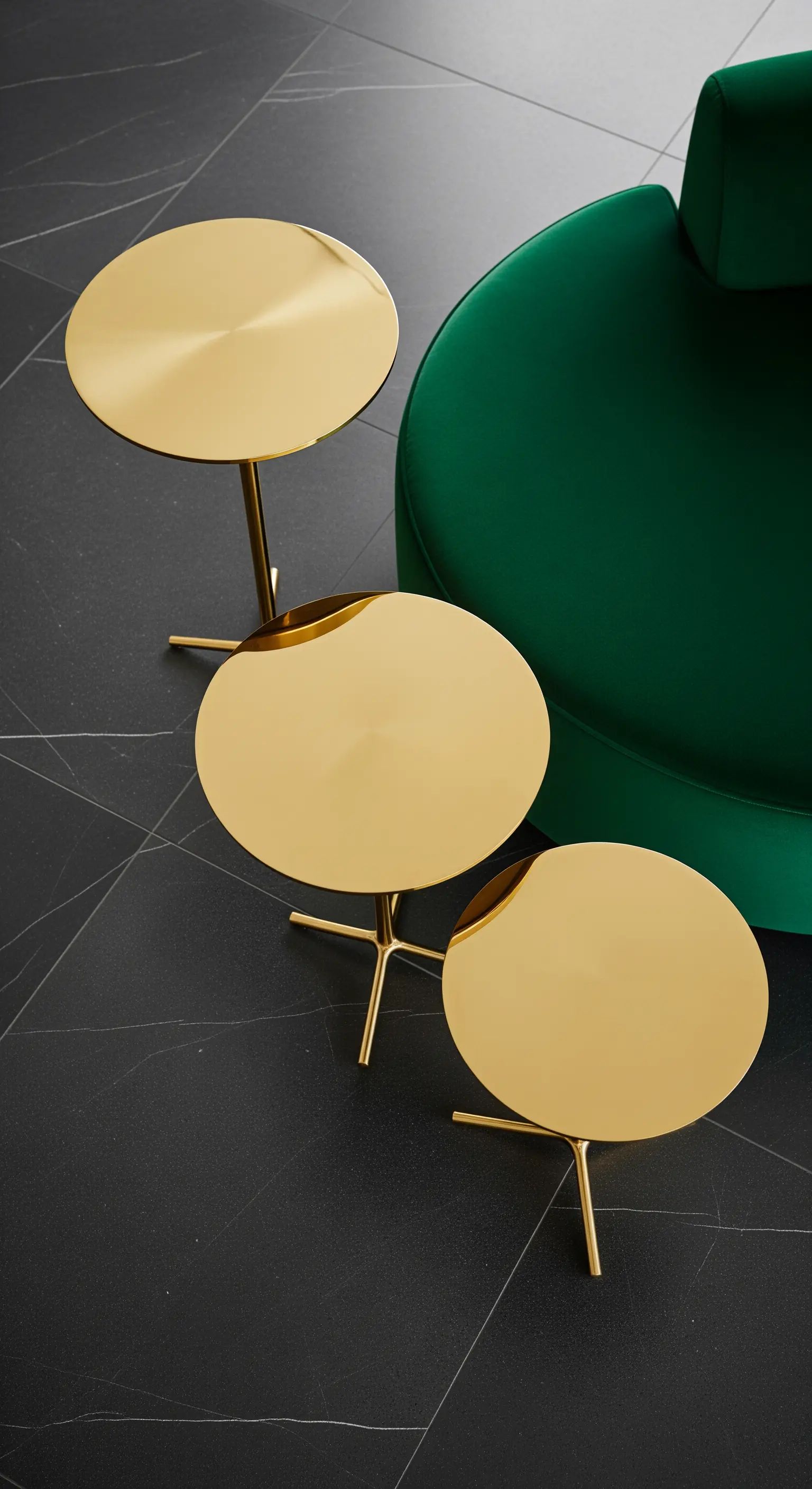 Drei gestaffelte runde Messing-Beistelltische vor einem grünen Sofa