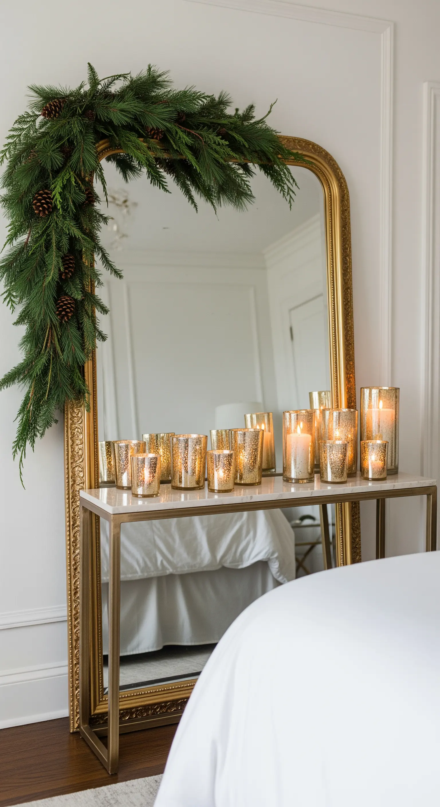 Goldener Spiegel und Konsole mit vielen Quecksilberglas-Windlichtern und Tannengirlande.
