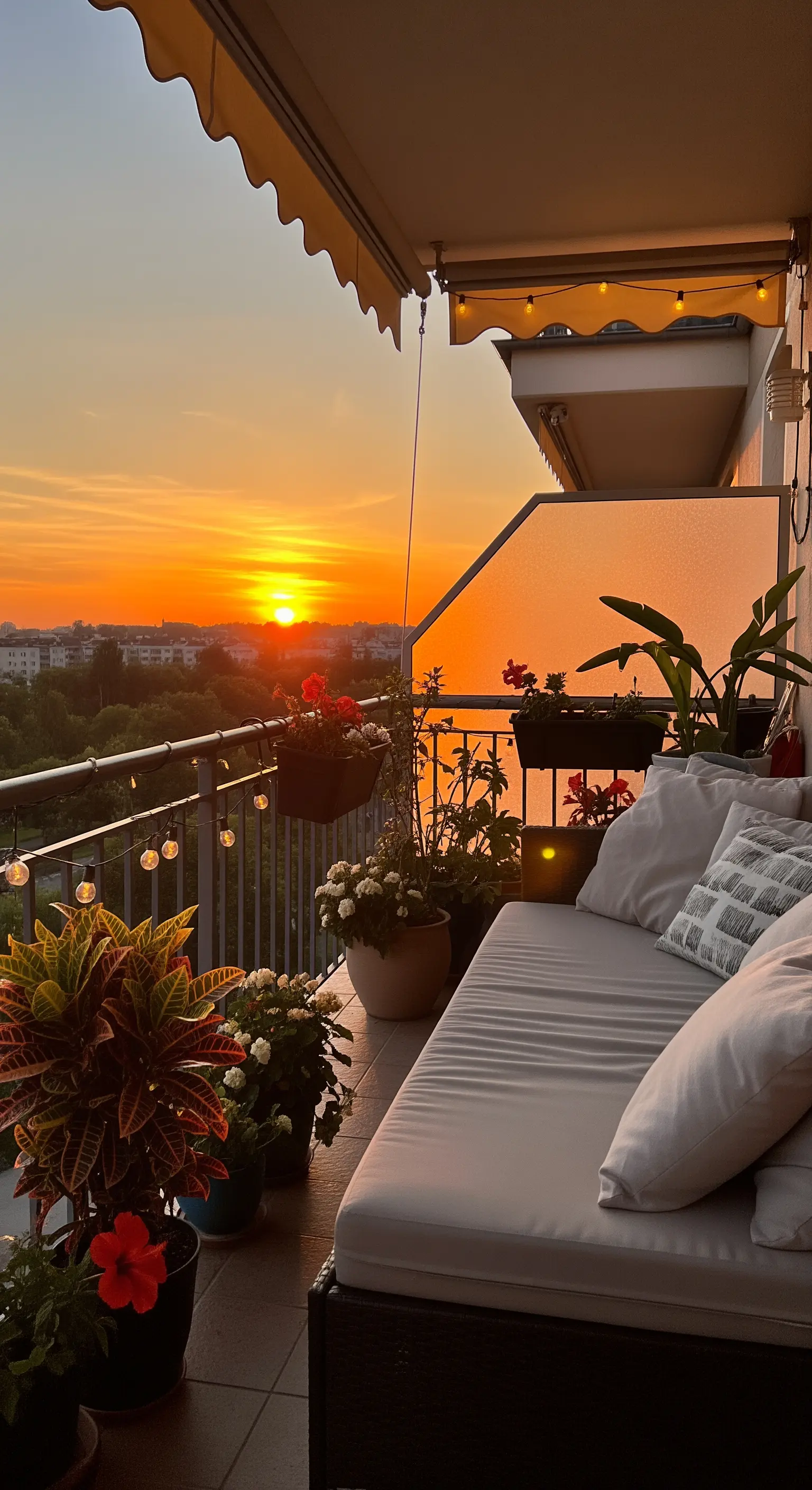 Gemütlicher Balkon mit einem Daybed und einer Lichterkette, die im warmen Licht des Sonnenuntergangs leuchtet.