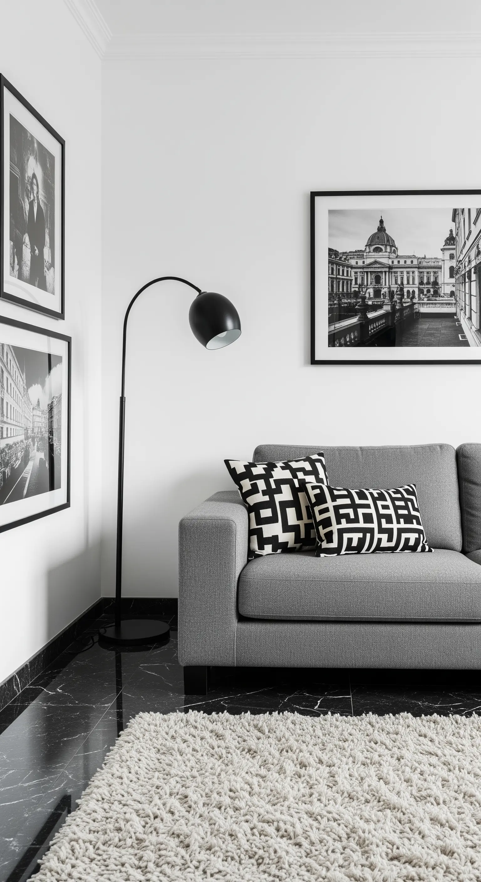 Minimalistisches Wohnzimmer mit schwarzem Marmorboden, grauem Sofa und schwarz-weißen Musterkissen.