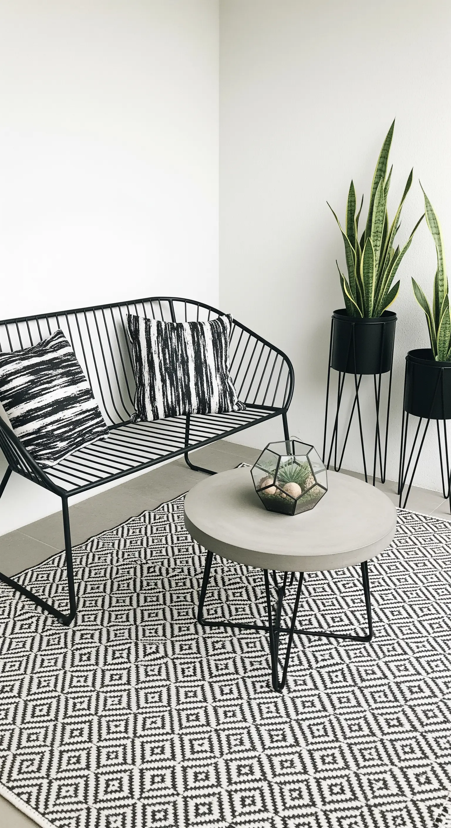 Moderner Balkon mit schwarzen Metallmöbeln und einem Teppich mit grafischem Muster.