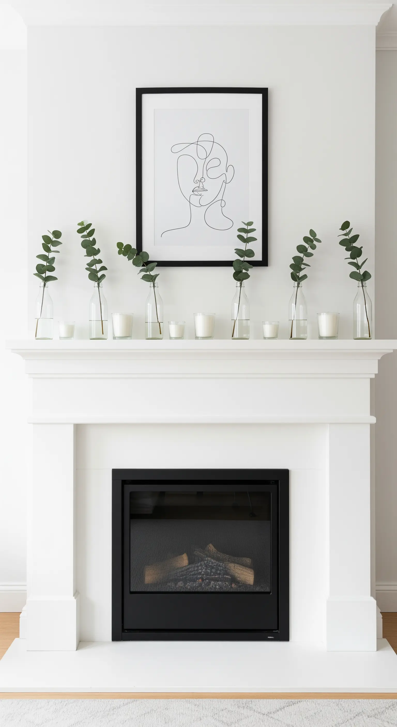 Minimalistische Kamin Deko mit Eukalyptuszweigen, weißen Kerzen und einem Line-Art Bild.