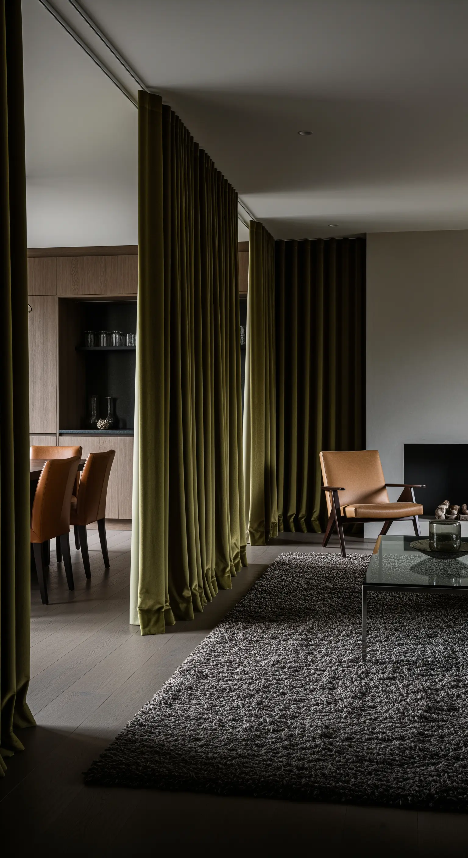 Grüne Samtvorhänge als Raumteiler in offenem Wohn-Essbereich mit Ledersessel