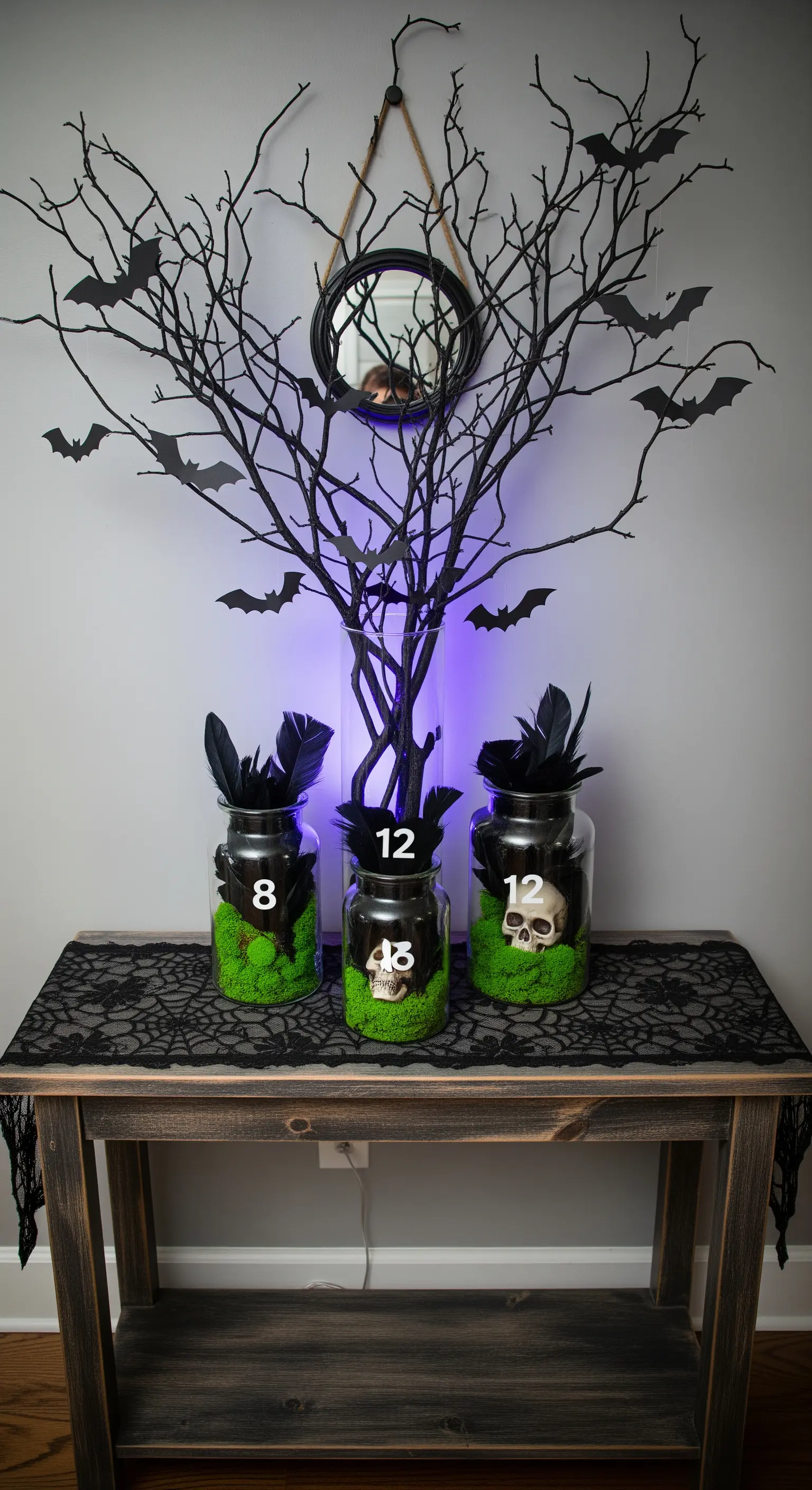 Halloween-Empfangstisch mit dunklen Ästen, Fledermäusen und Leuchtgläsern.