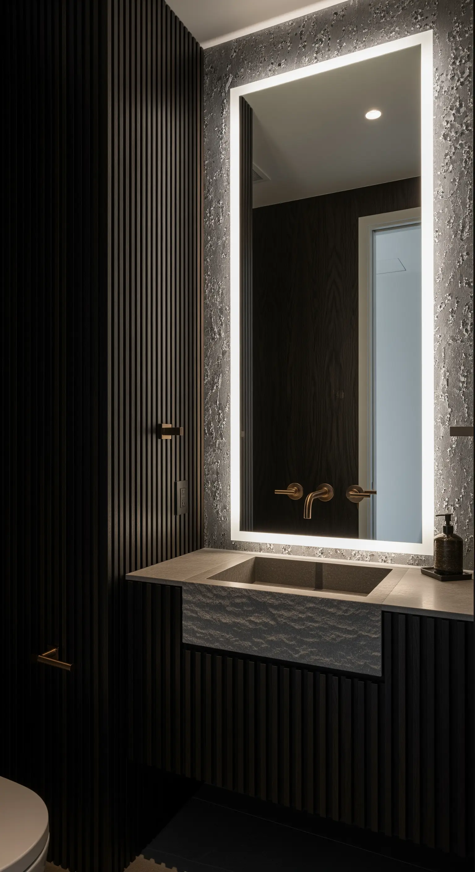 Badezimmer mit dunkler Lamellenwand und einem großen, von hinten beleuchteten Spiegel.