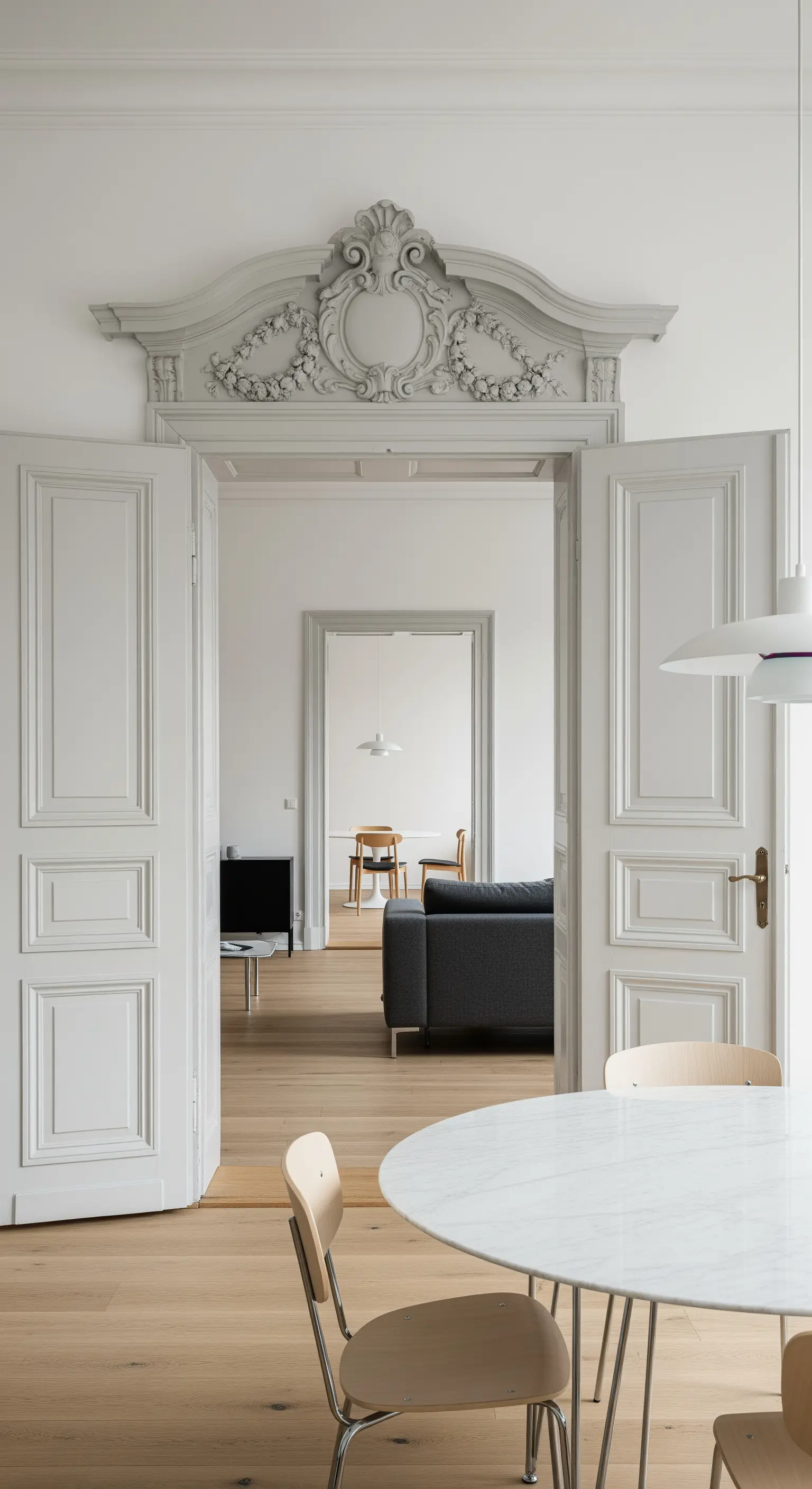 Blick durch eine verzierte, graue Altbautür in ein minimalistisch eingerichtetes Zimmer.