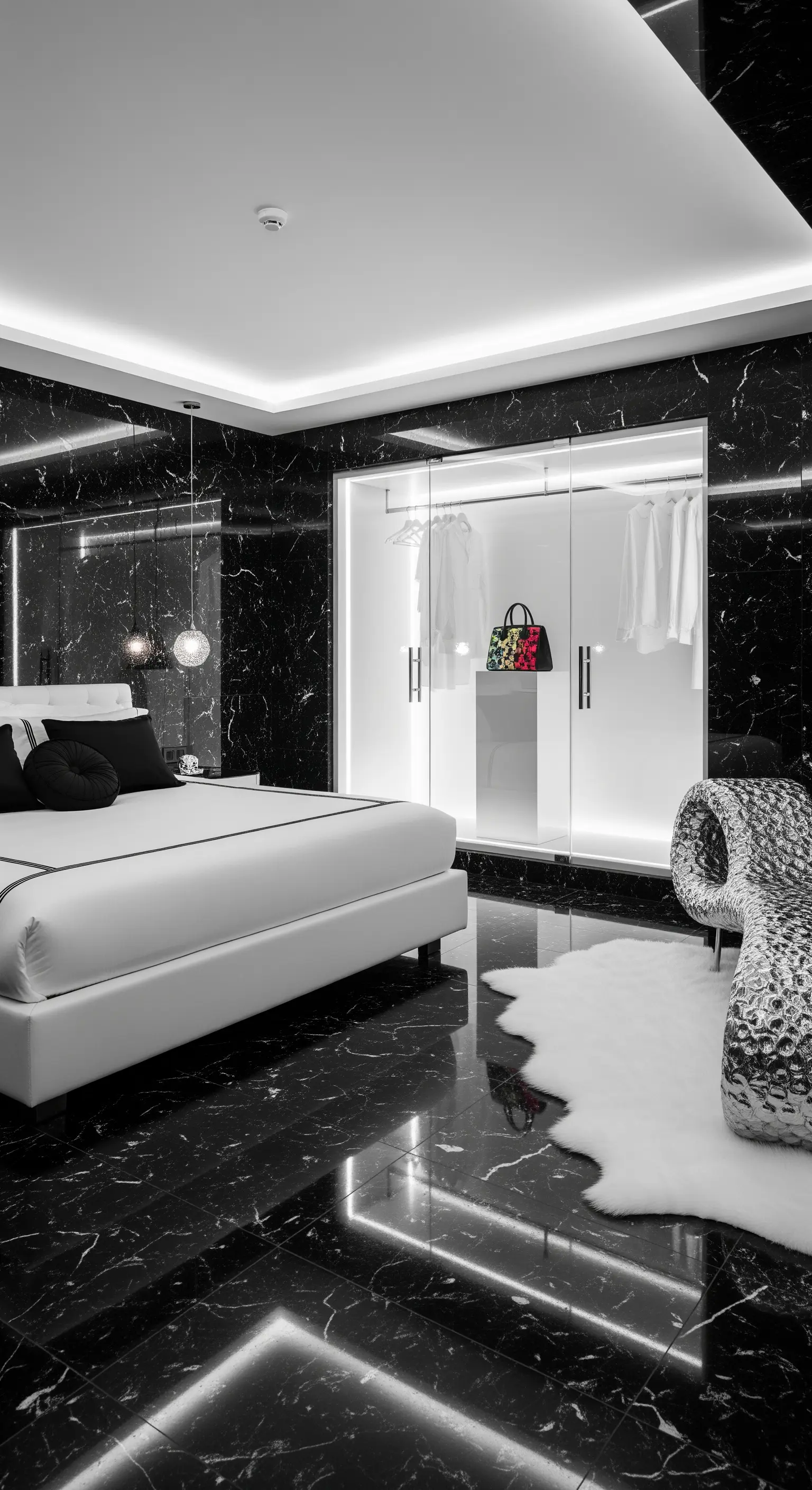 Luxuriöses Schlafzimmer mit schwarzem Marmor und einem hell erleuchteten weißen Glas-Kleiderschrank.