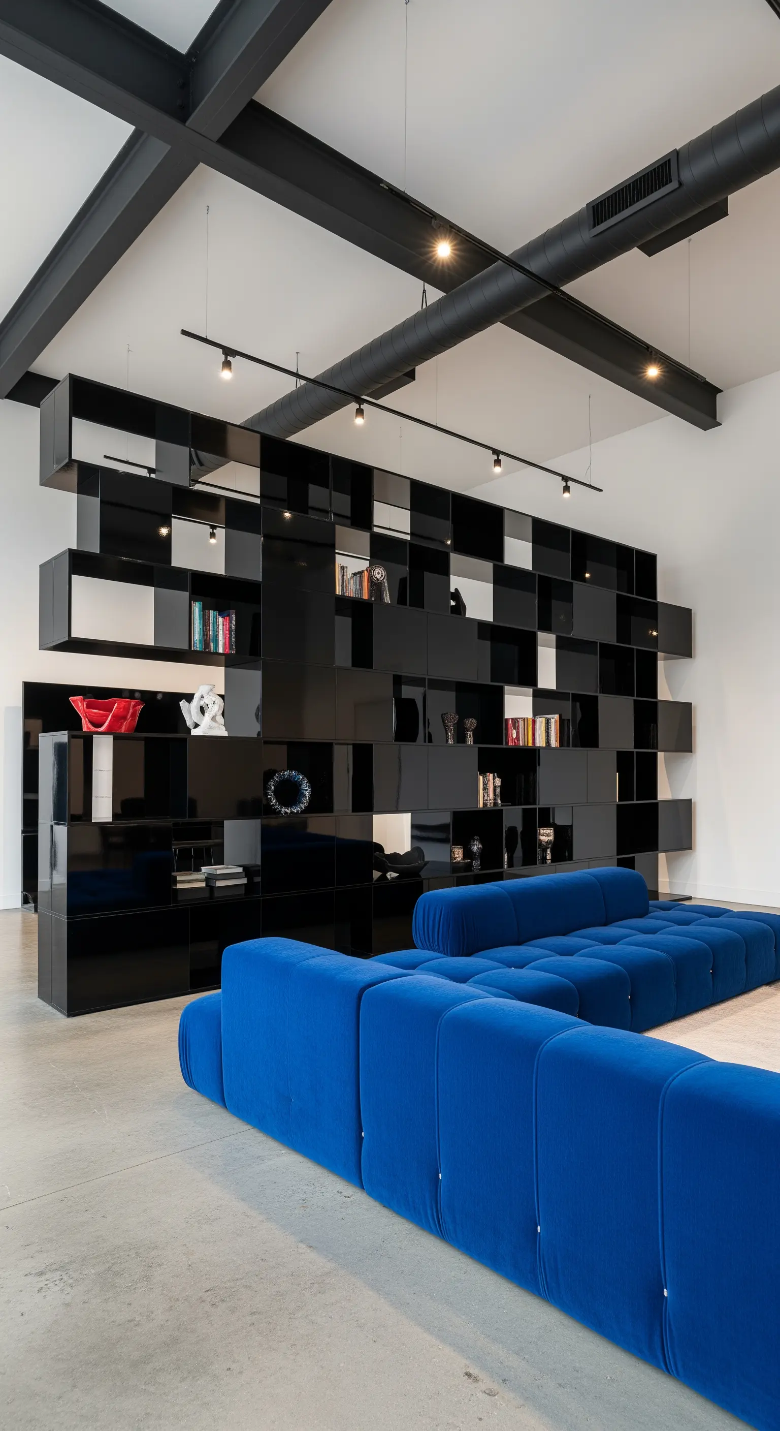 Schwarzes modulares Hochglanz-Regal in einem Loft mit blauer Couch und sichtbaren Deckenbalken.