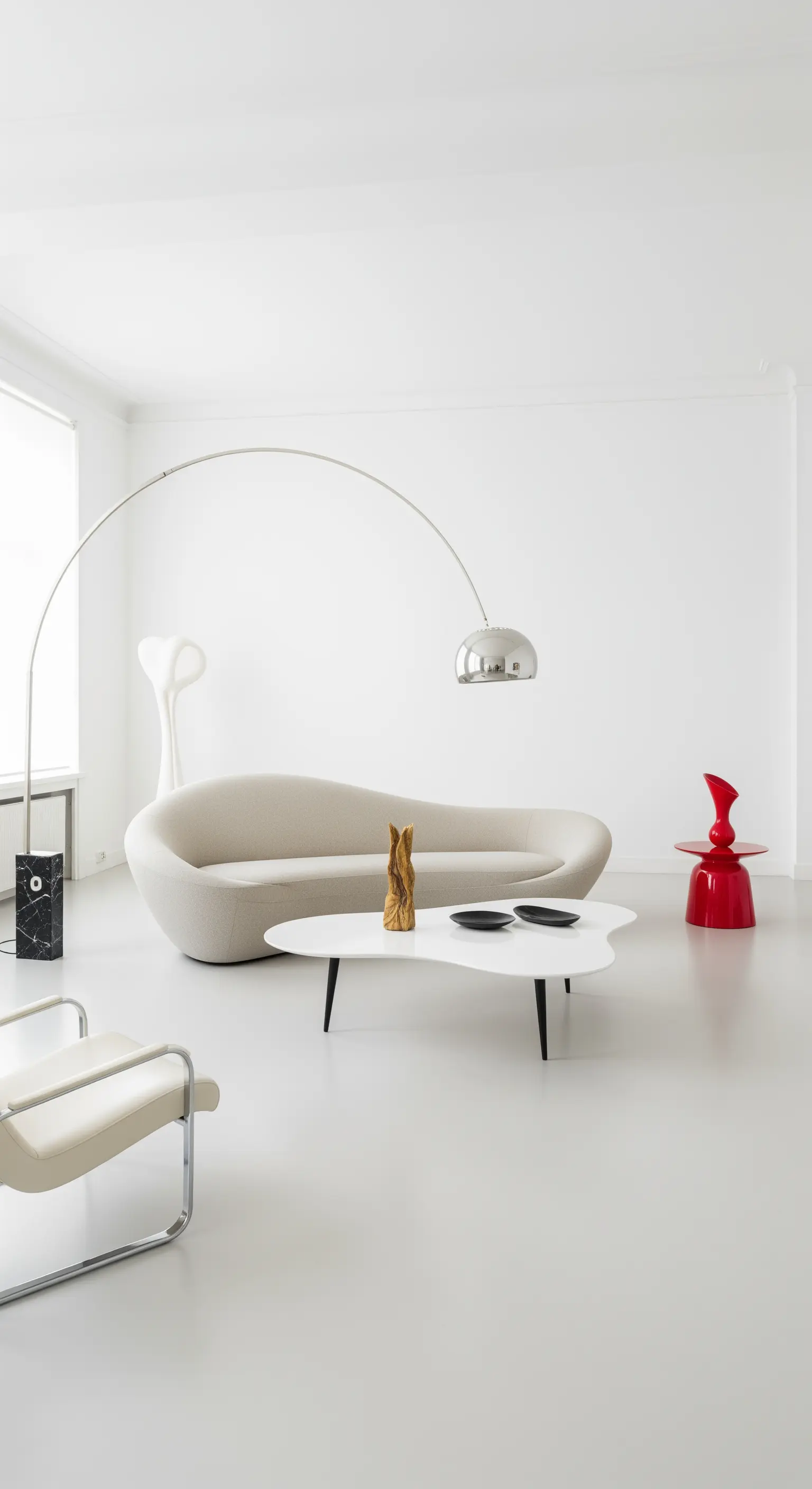 Weißes minimalistisches Wohnzimmer mit einem geschwungenen Sofa, einer Bogenleuchte und einem roten Akzenttisch.