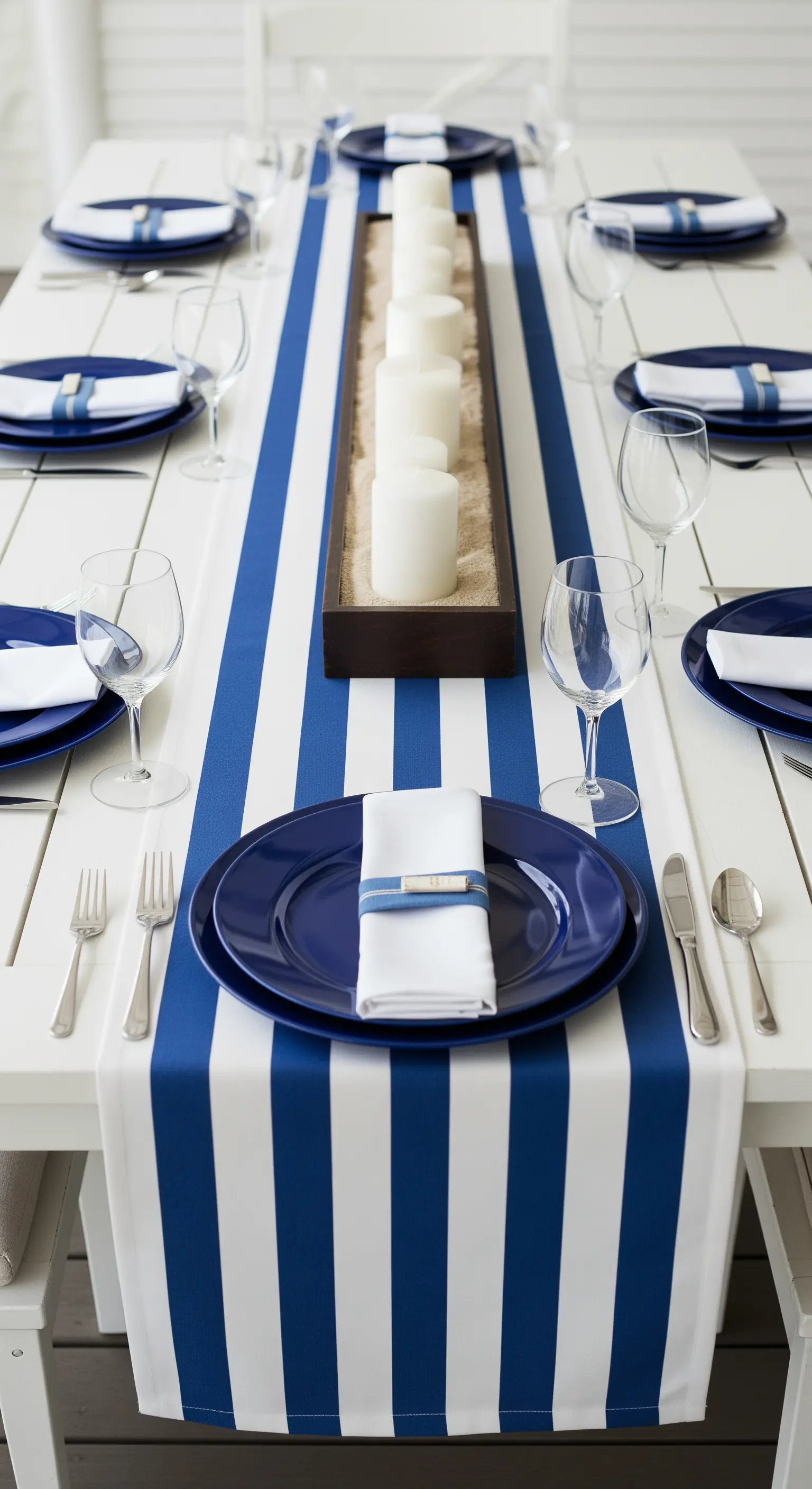 Tischdeko mit einem blau-weiß gestreiften Tischläufer und marineblauem Geschirr.