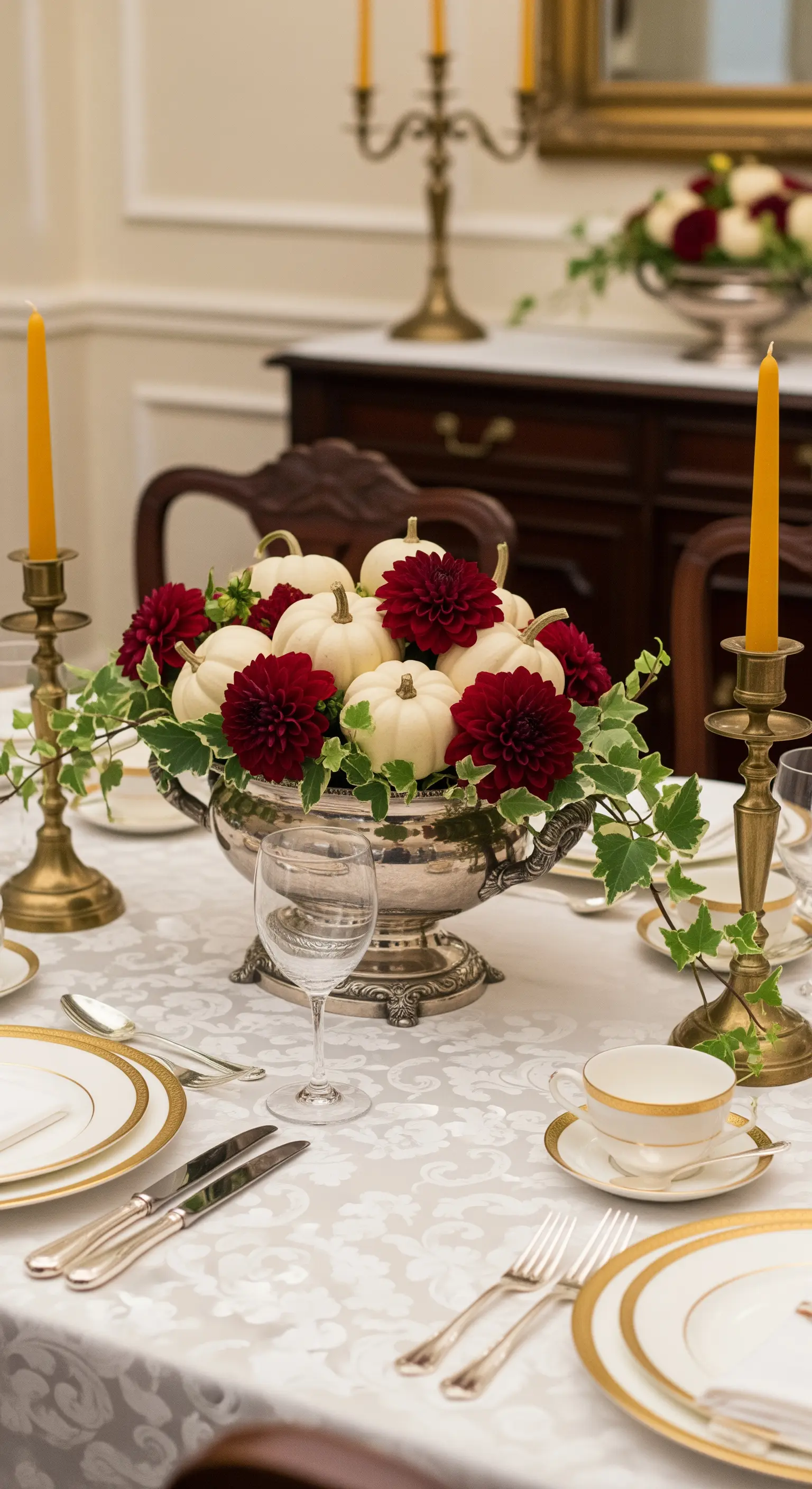 Elegantes Arrangement mit weißen Mini-Kürbissen und roten Dahlien in einer Silberschale.