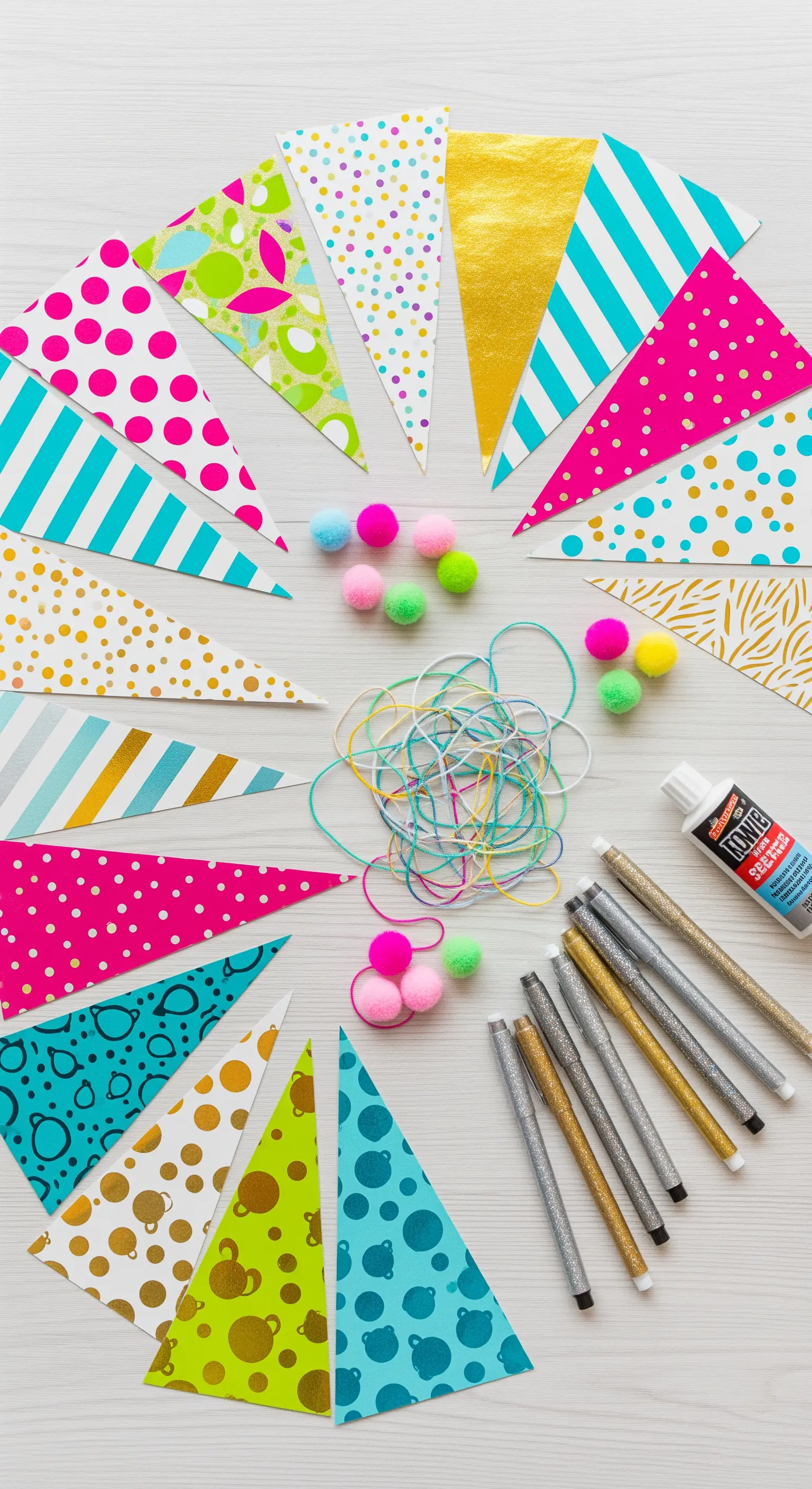 Bastelmaterialien für eine DIY-Girlande mit bunten Dreiecken und Glitzerstiften.