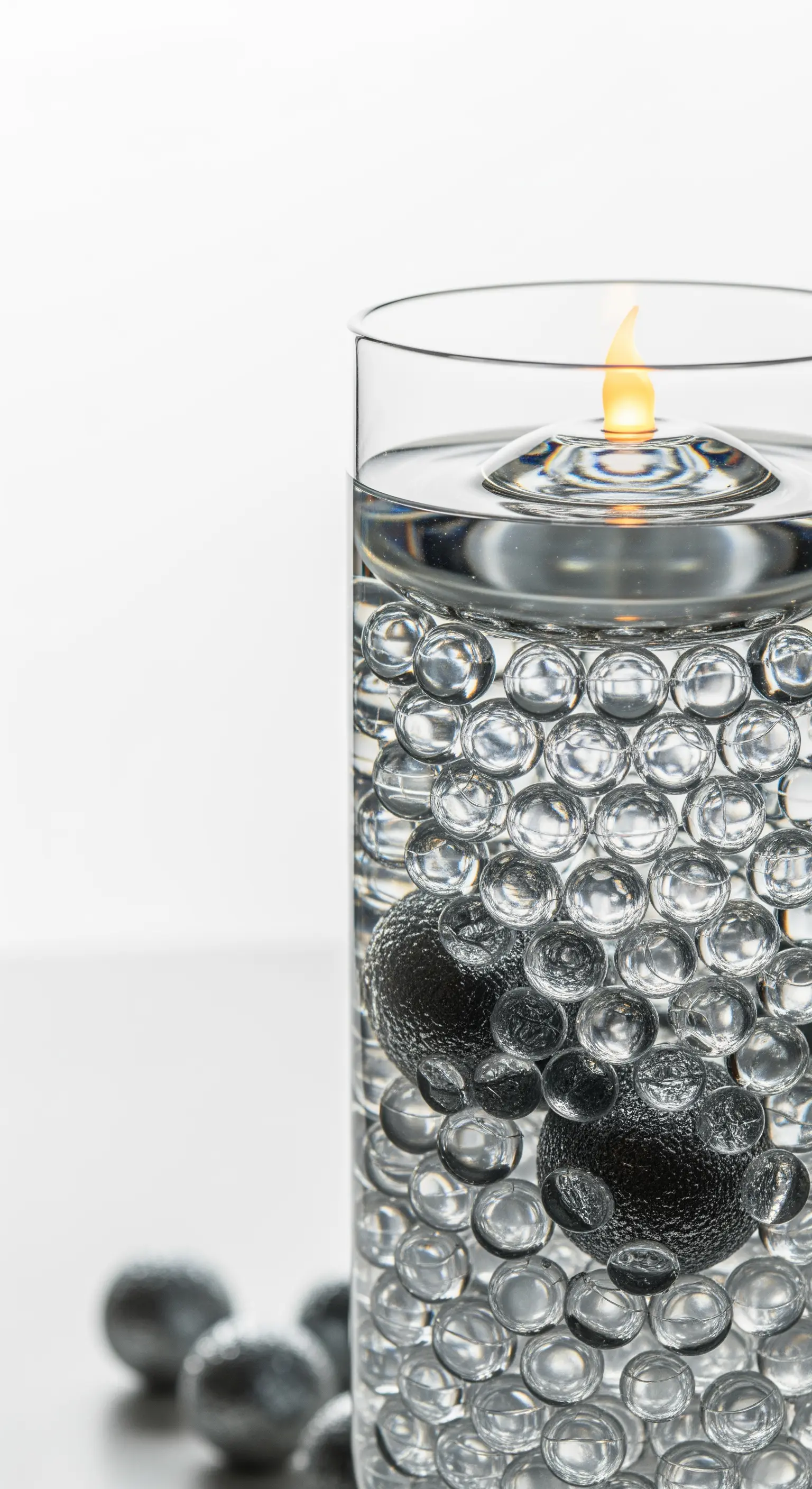 Minimalistische Glasvase mit Wasserperlen und einer schwimmenden Ölkerze.
