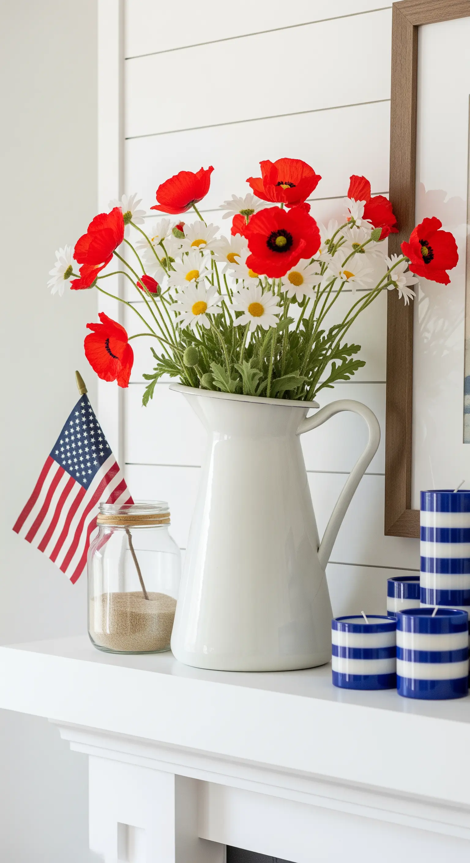 Patriotische Sommerdeko mit Mohnblumen in einem weißen Krug und blau-weiß gestreiften Kerzen.