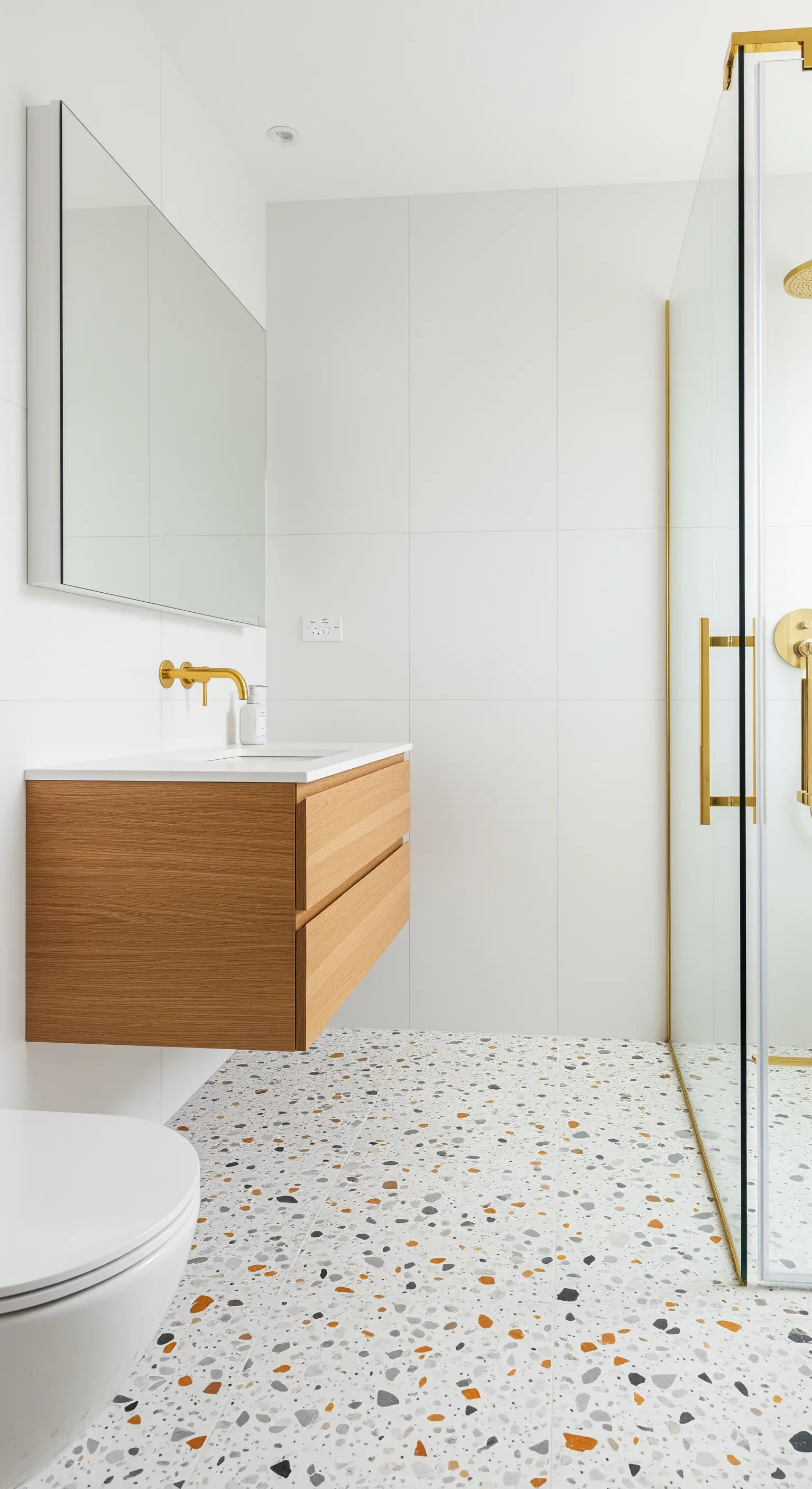 Minimalistisches Bad mit buntem Terrazzo-Boden und schwebendem Holzwaschtisch.