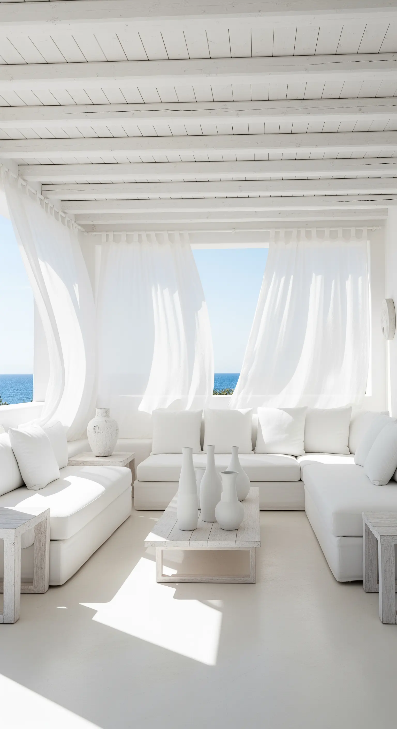 Weiße Veranda mit bequemen Sofas, fließenden Vorhängen und Meerblick