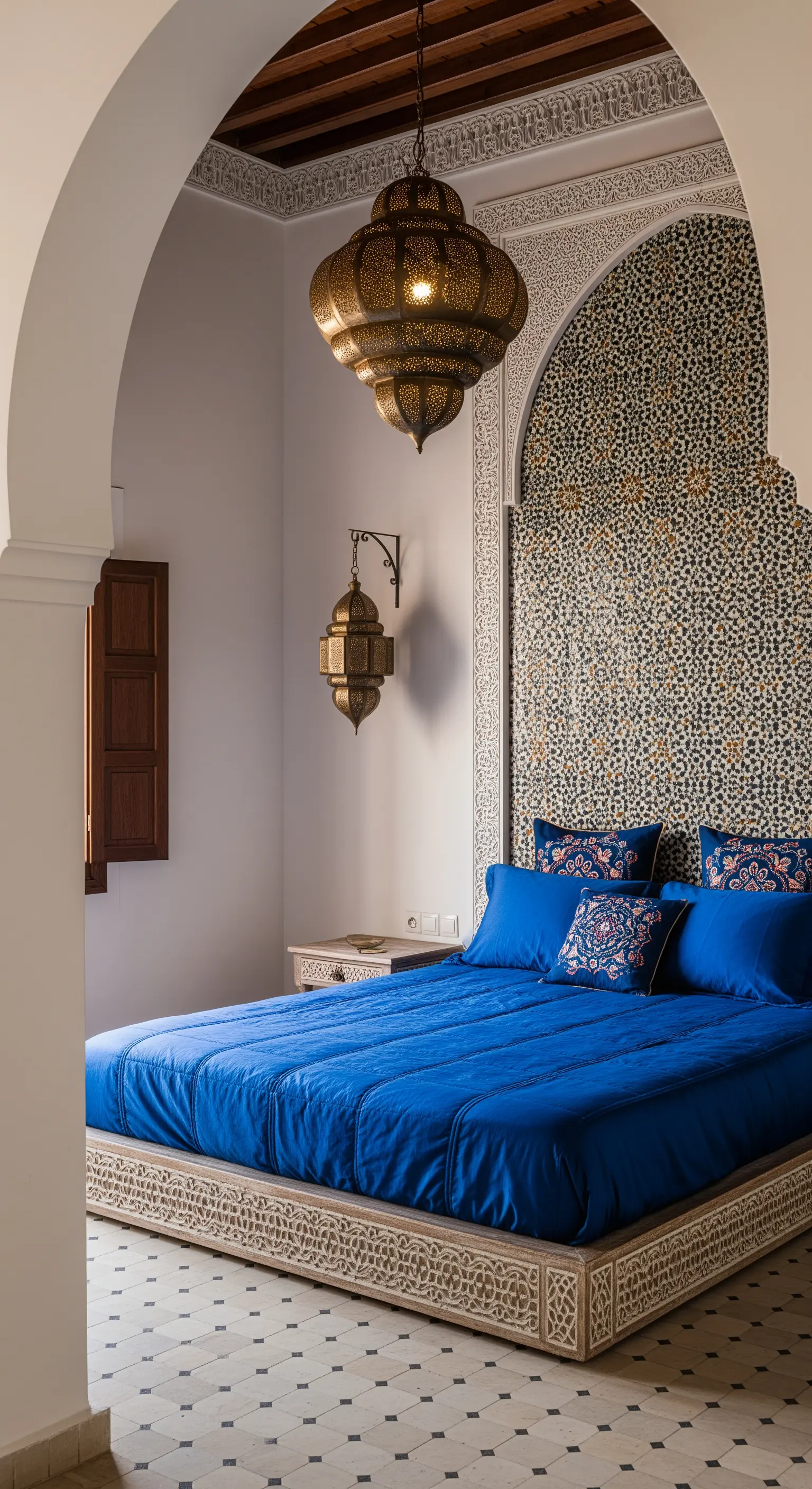 Marokkanisches Schlafzimmer mit Mosaikwand, einer großen Metalllaterne und kobaltblauer Bettwäsche.