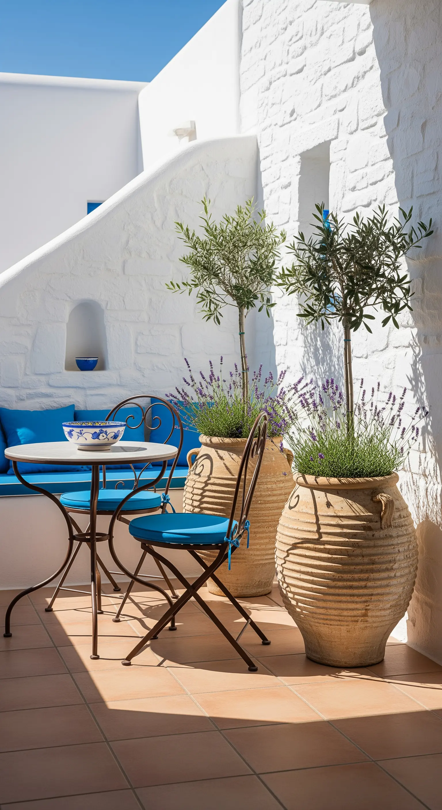 Mediterraner Balkon mit blauen Akzenten, weißen Wänden und Terrakotta-Pflanzgefäßen