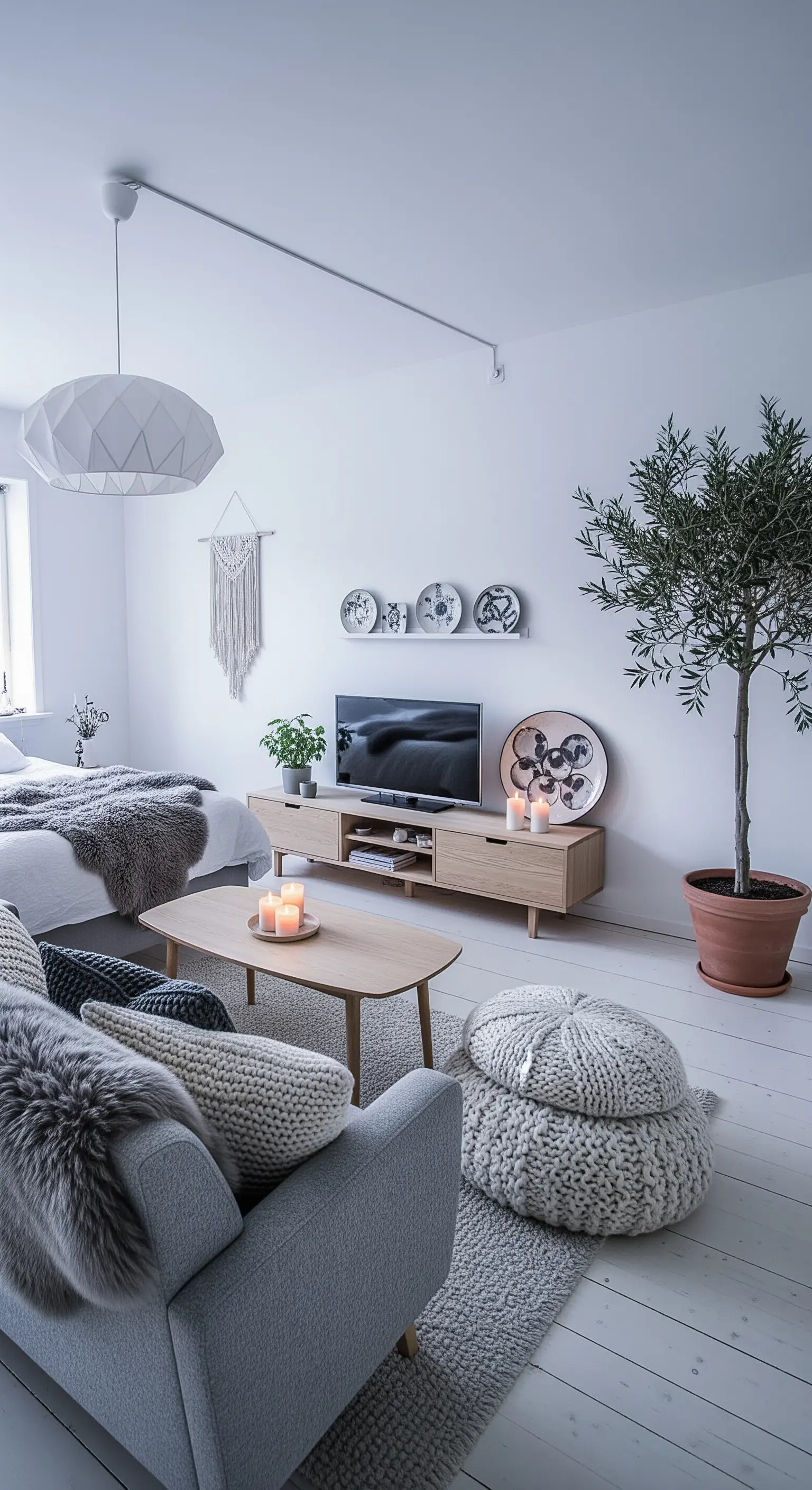 Weißes minimalistisches Zimmer mit einem großen Olivenbaum im Topf und grauen Strick-Poufs