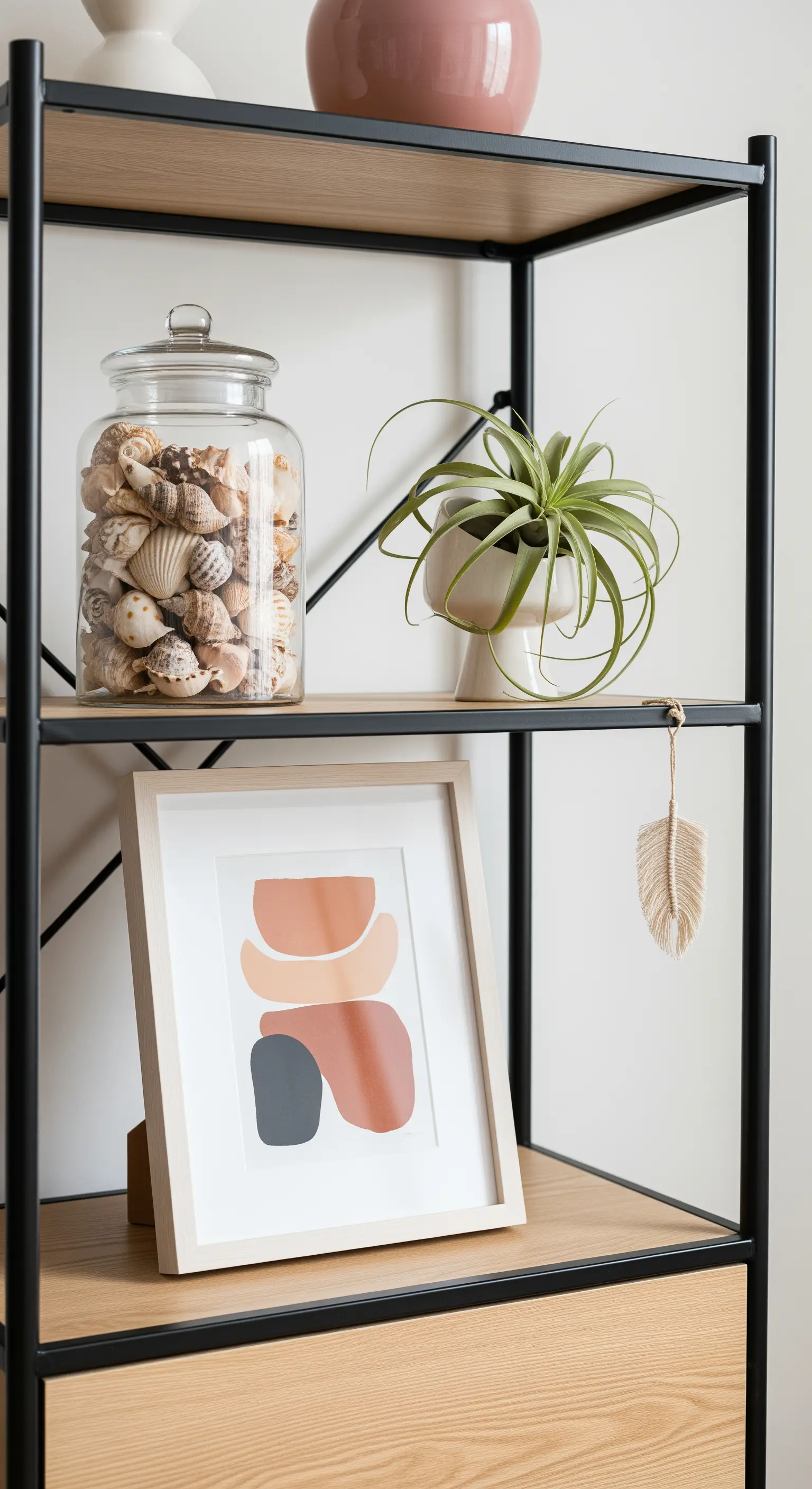 Modernes Boho-Regal mit Muschelglas, abstraktem Bild und Luftpflanze.