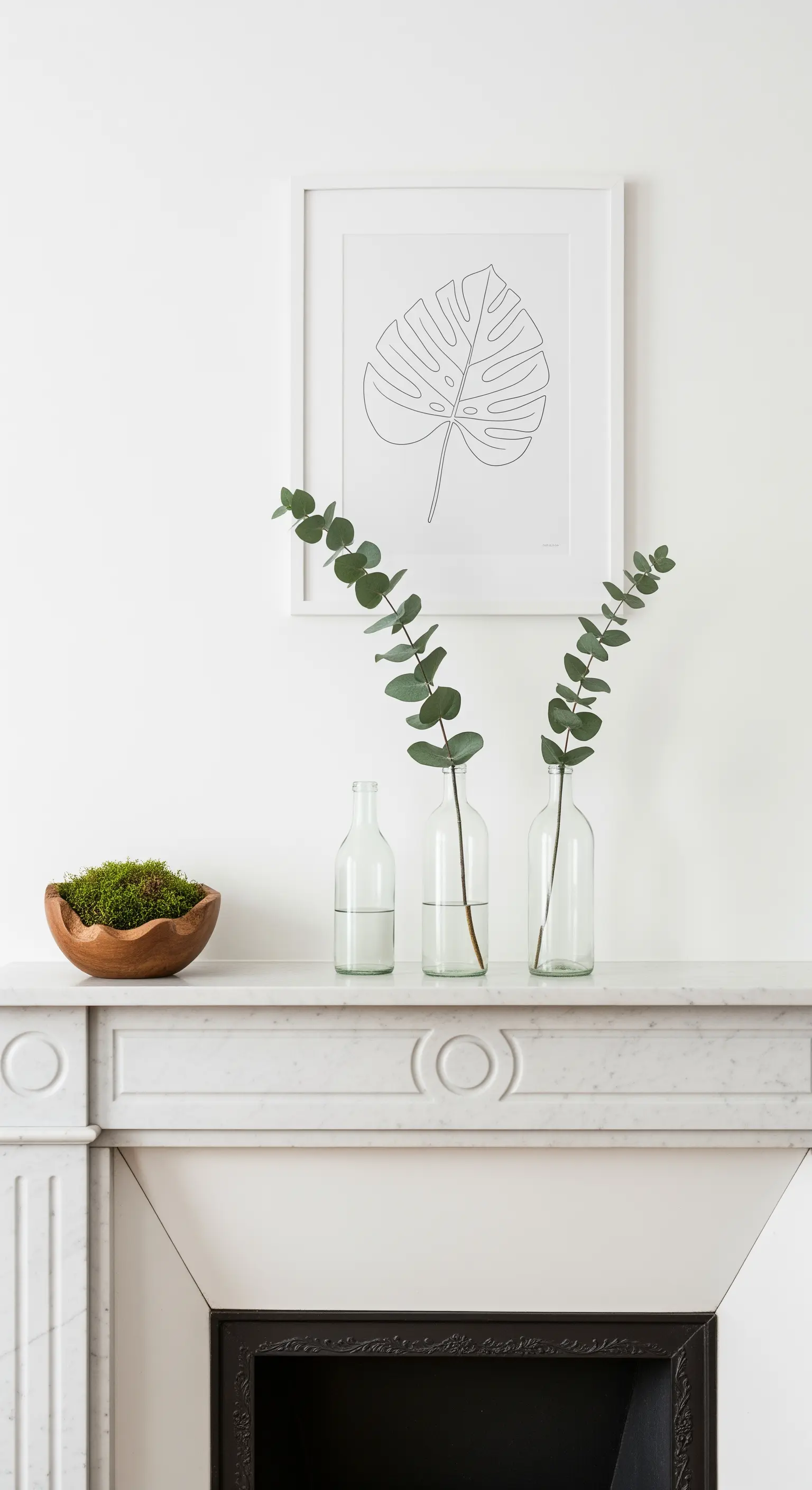 Minimalistische Deko auf Marmor-Kaminsims mit Eukalyptus, Moos und einem Blatt-Kunstdruck