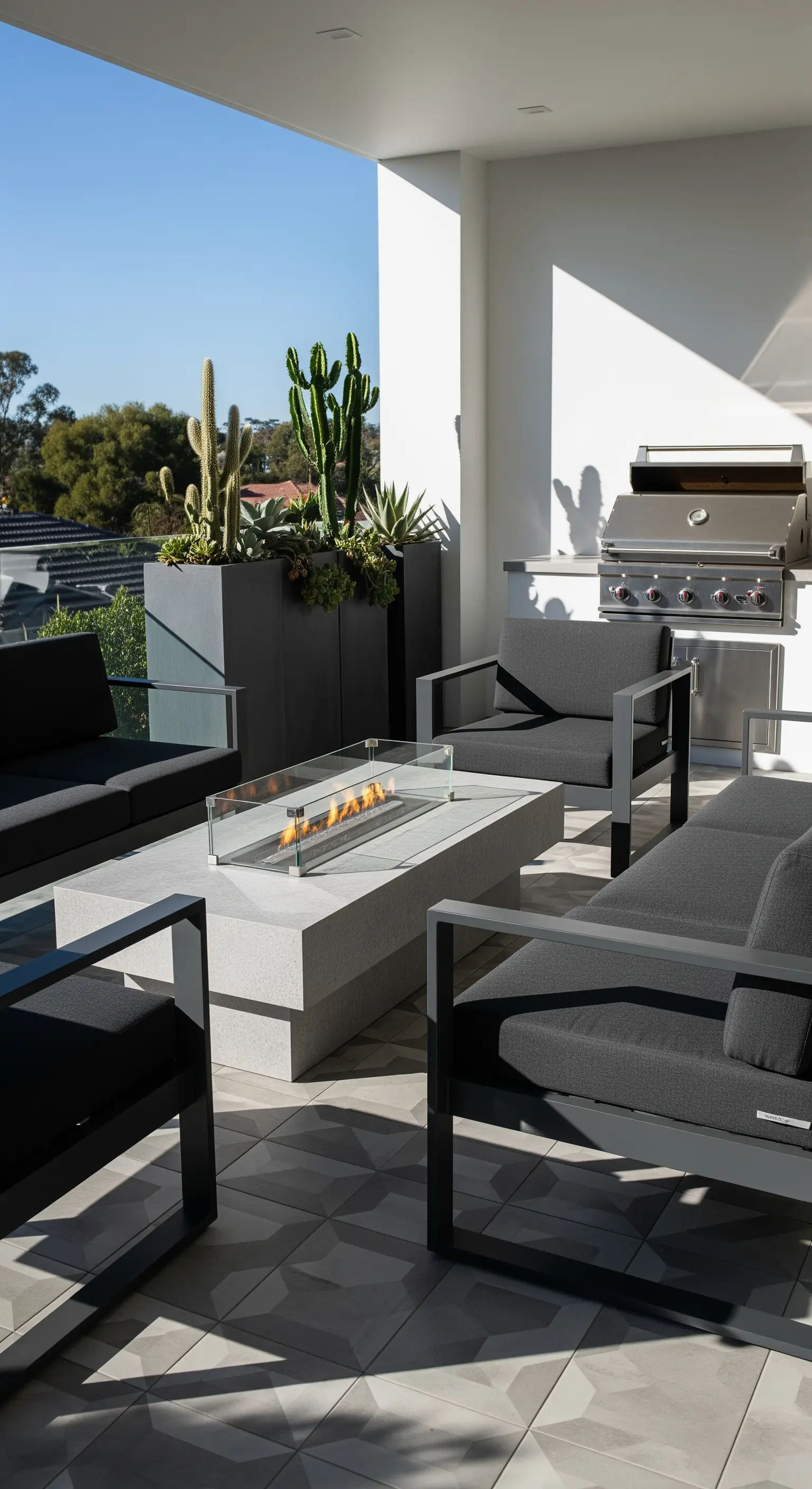 Sleeke Outdoor-Lounge mit Gaskamin, dunklen Sofas und architektonischen Pflanzen