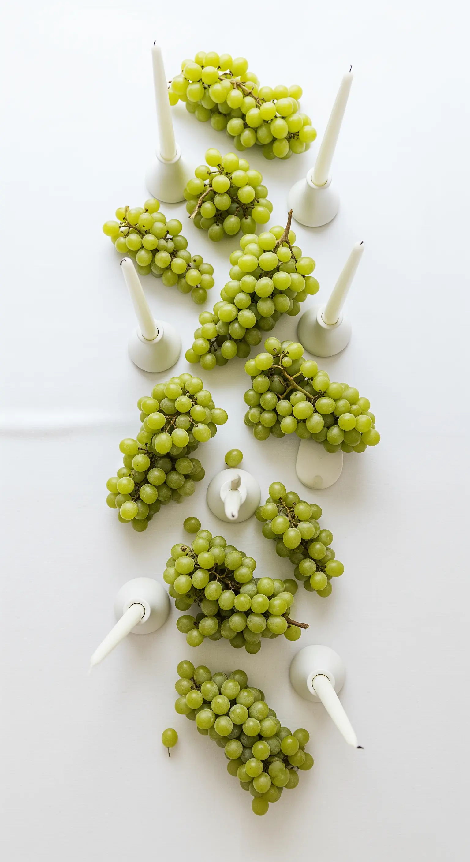 Minimalistischer Tischläufer aus hellgrünen Trauben mit weißen Kerzenständer