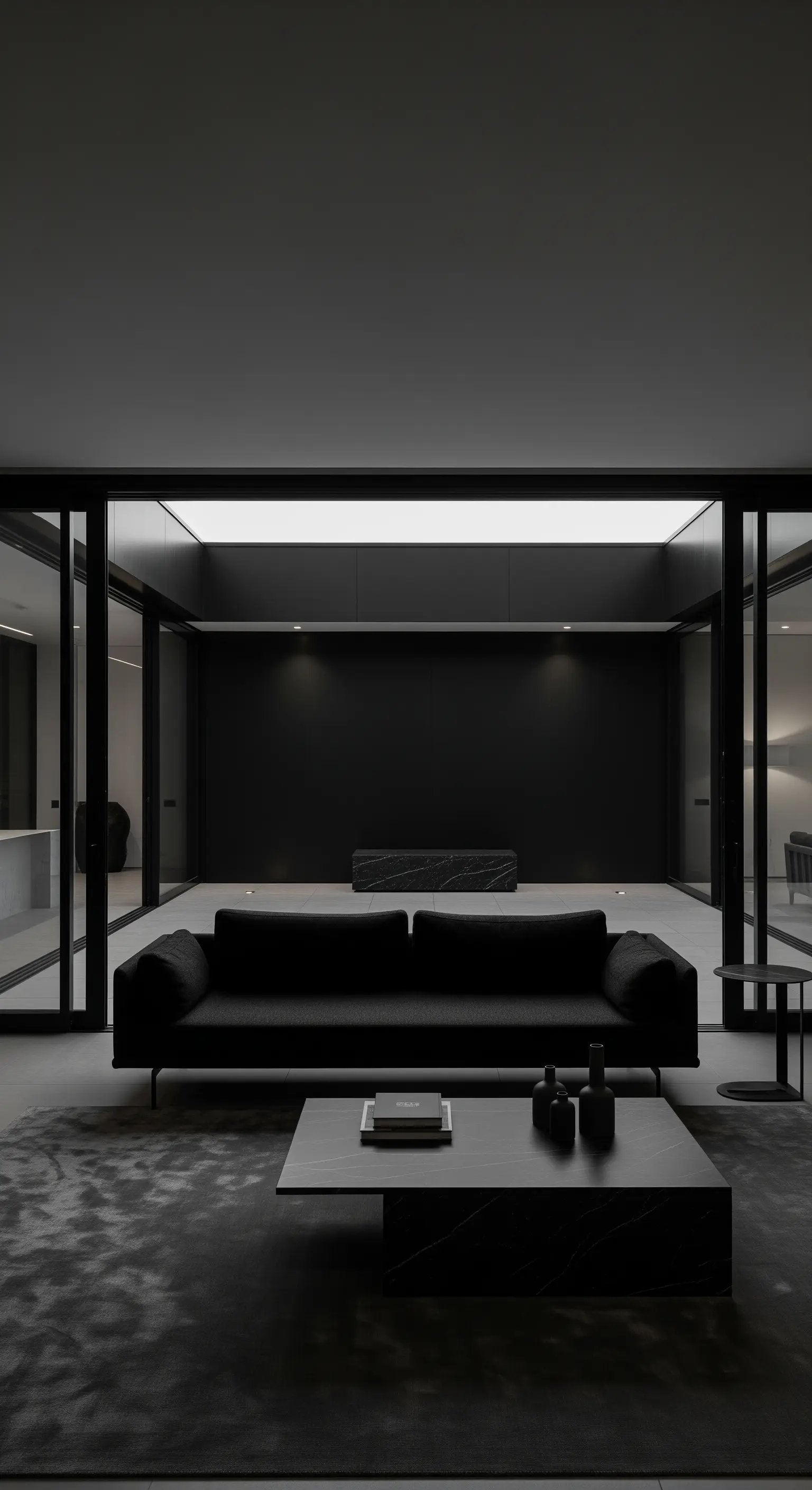 Minimalistischer Wohnraum mit Glasschiebetüren, schwarzem Sofa und dunklem Teppich