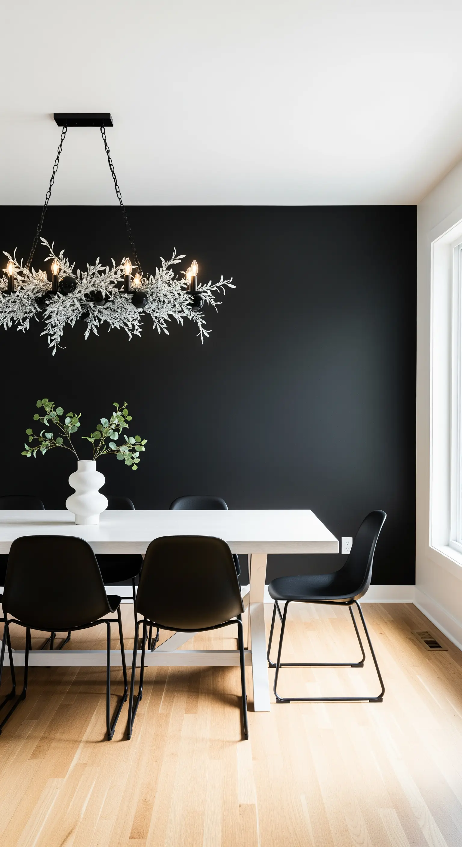 Esszimmer mit schwarzer Akzentwand, weißem Tisch und minimalistischer Leuchte.