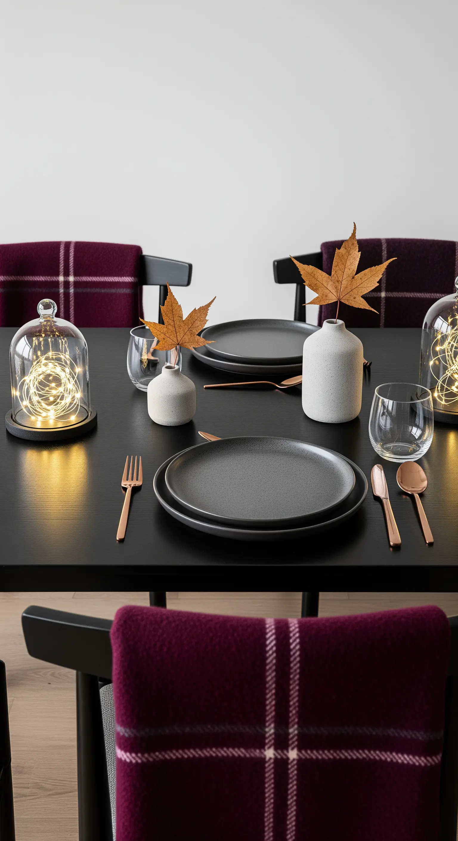 Moderne Herbsttafel, dunkle Töne, Lichterketten unter Glasglocken, Ahornblatt-Akzente.