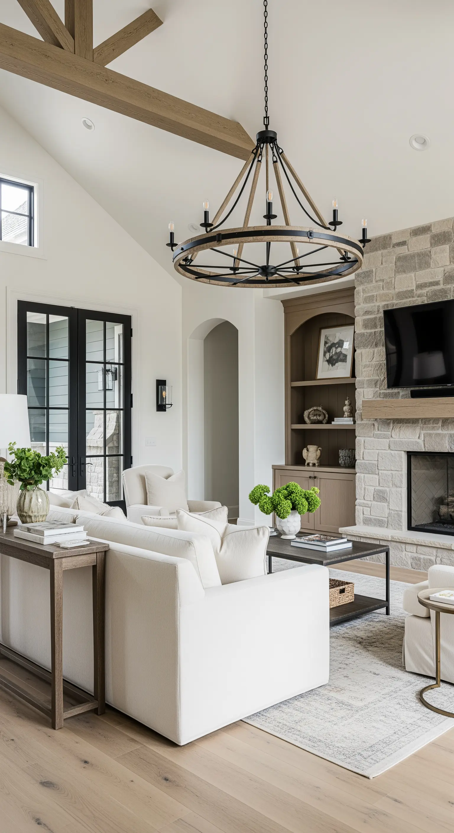 Weisse Sofas in einem modernen Landhaus-Wohnzimmer mit Steinkamin und Holzbalken.
