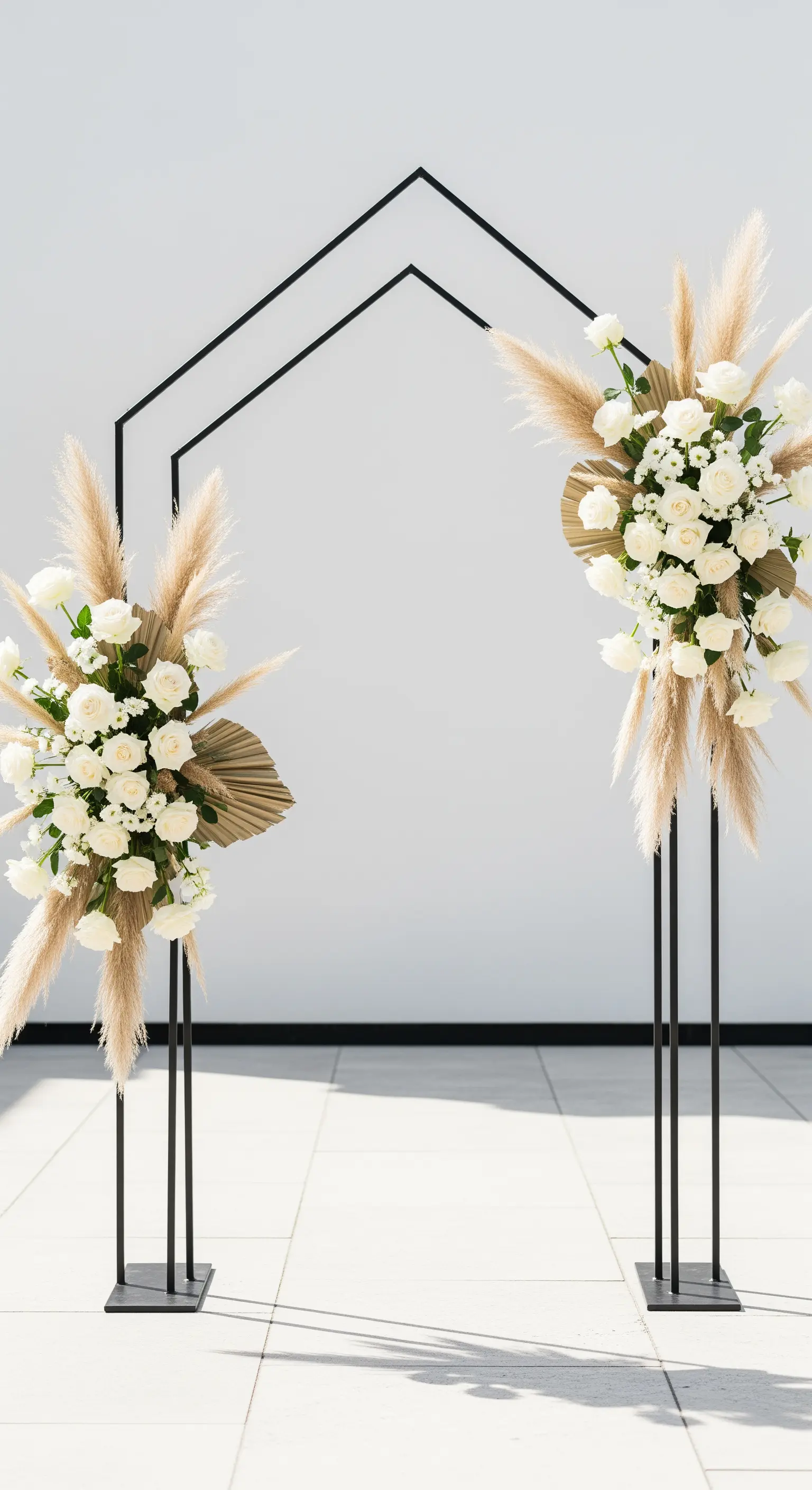 Moderne schwarze geometrische Bögen, dekoriert mit weißen Rosen, Grün, Pampasgras und Palmwedeln.