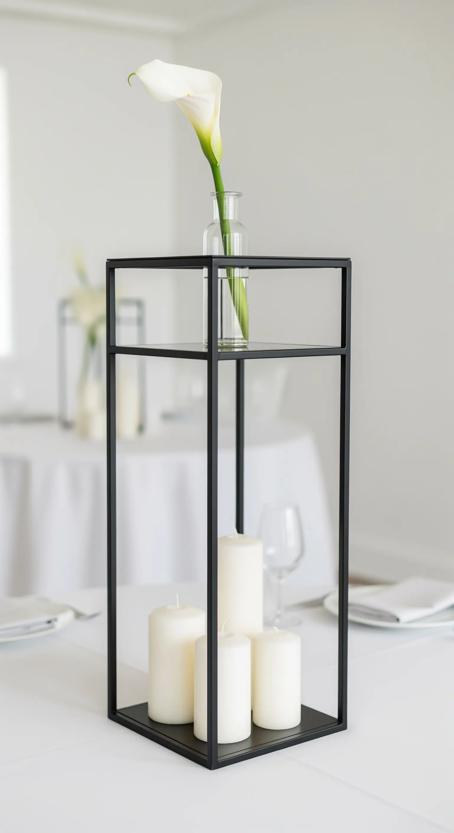 Schwarze, minimalistische Metall-Etagere mit einer Calla-Lilie und weißen Kerzen.