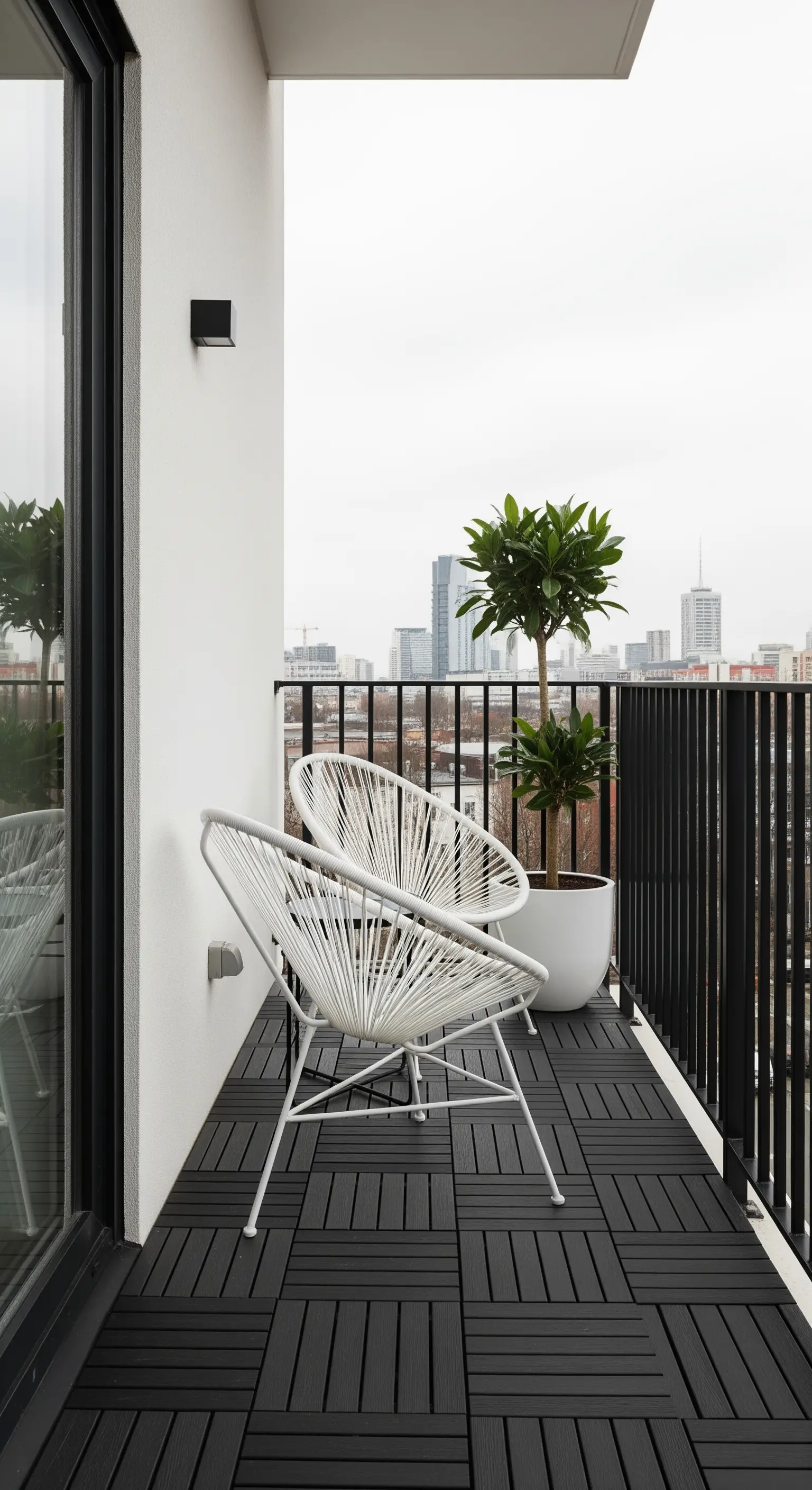 Minimalistischer Balkon mit schwarzen Bodenfliesen und weißen Acapulco-Stühlen.