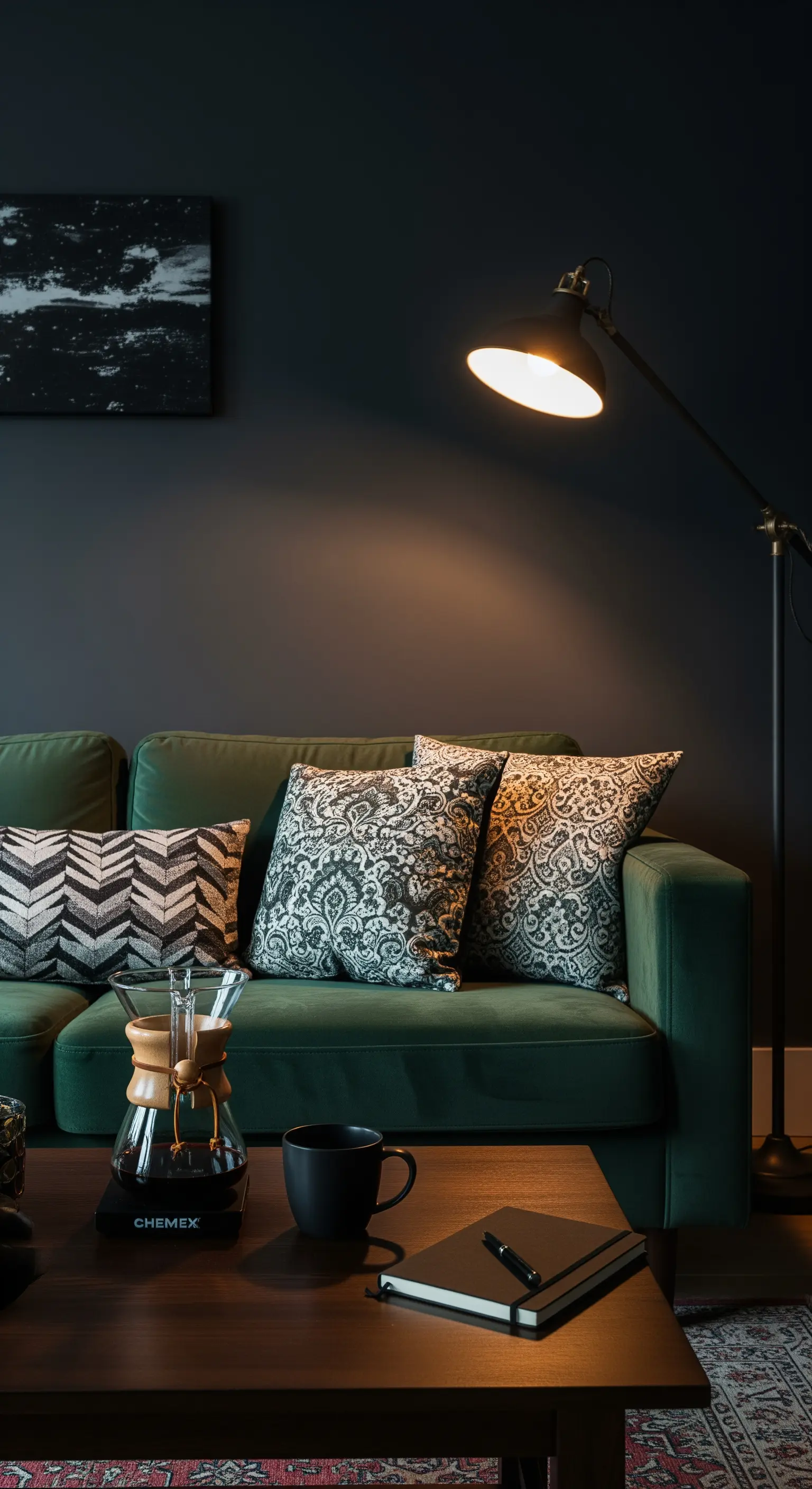 Dunkles Wohnzimmer mit grünem Samtsofa, das von einer Stehlampe angestrahlt wird.