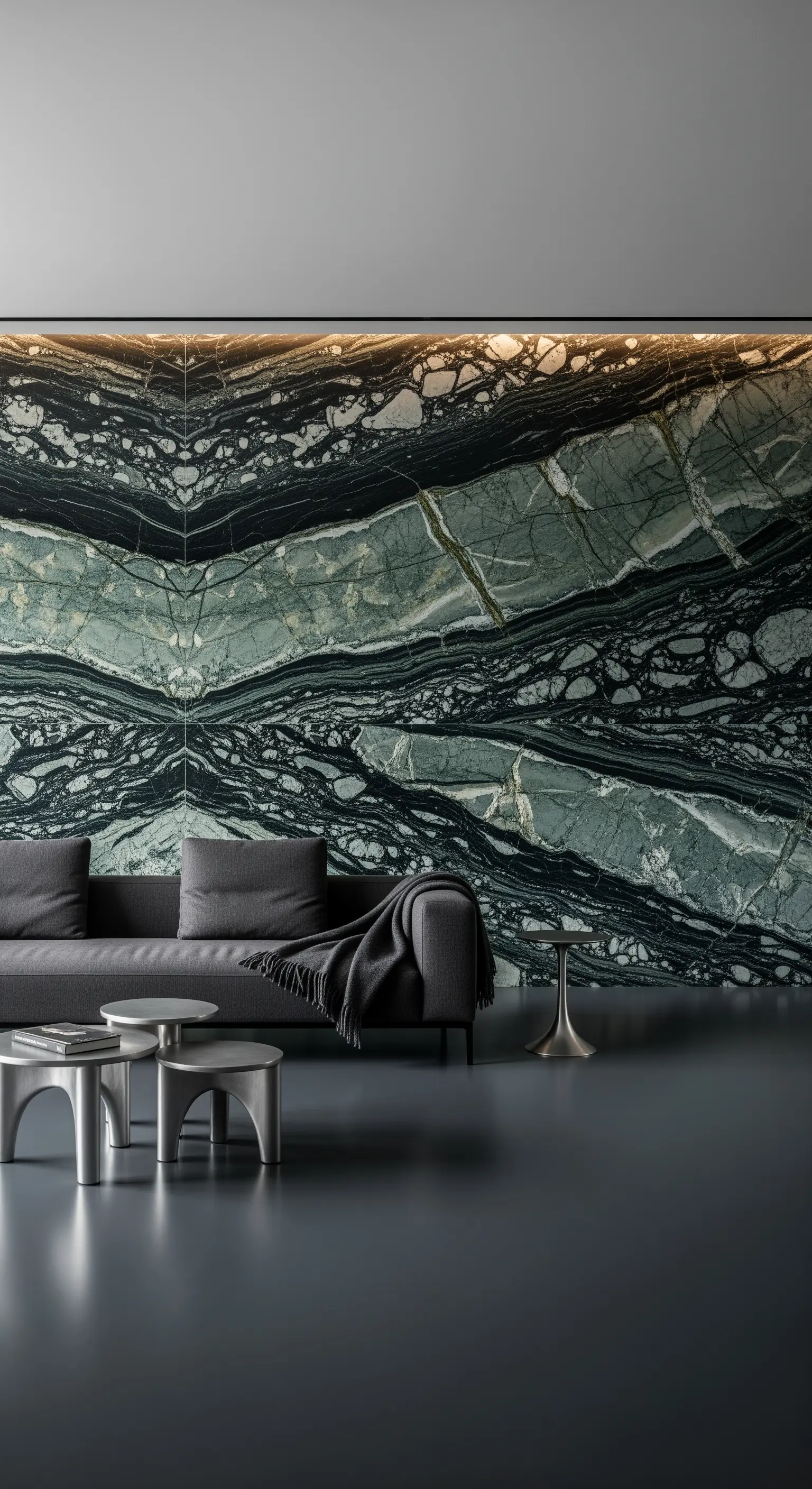 Eine riesige, symmetrisch gemaserte Marmorwand als Kunstwerk hinter einem grauen Sofa.
