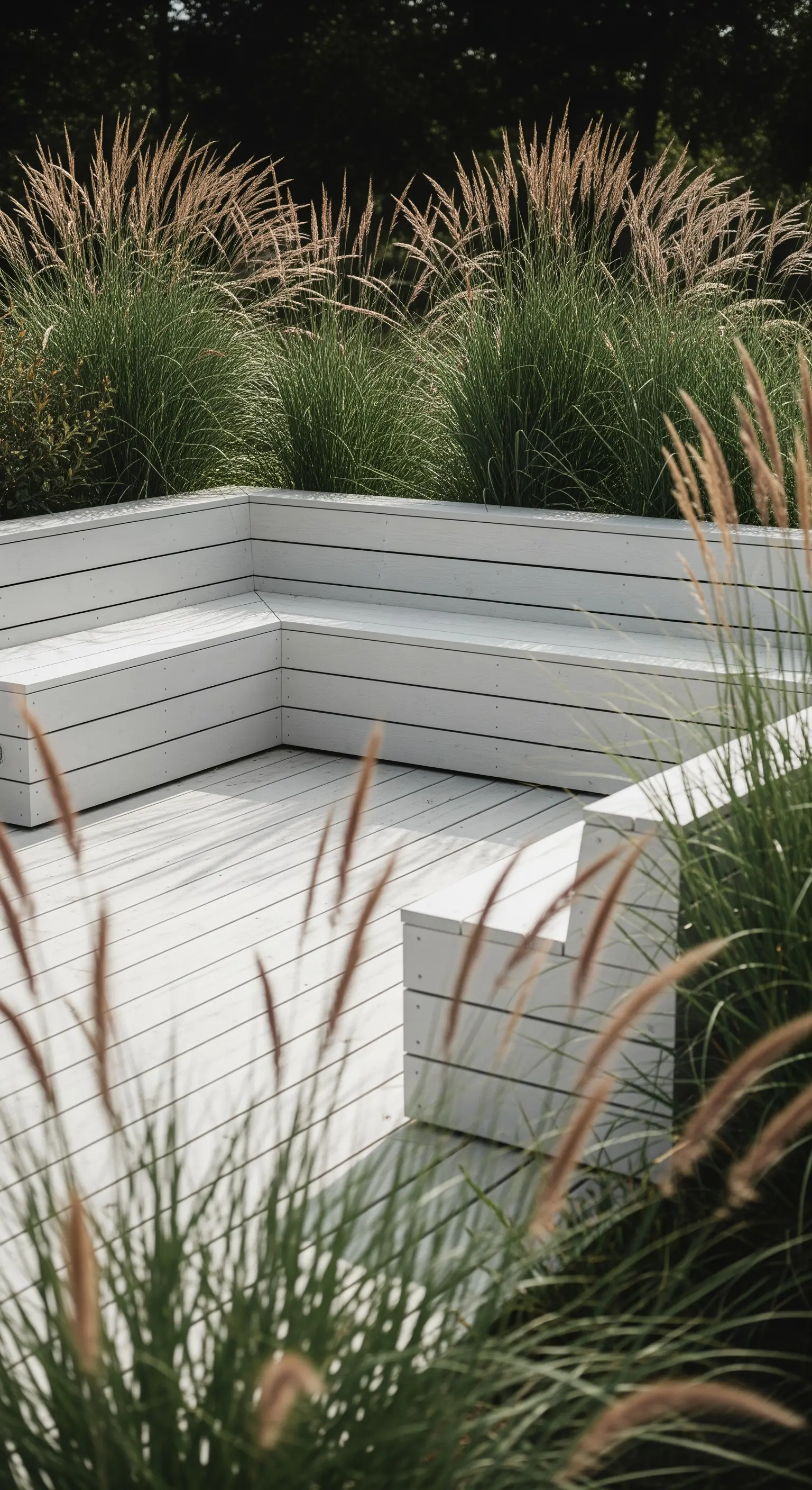 Weißes Holzdeck mit Bänken und hohen Gräsern