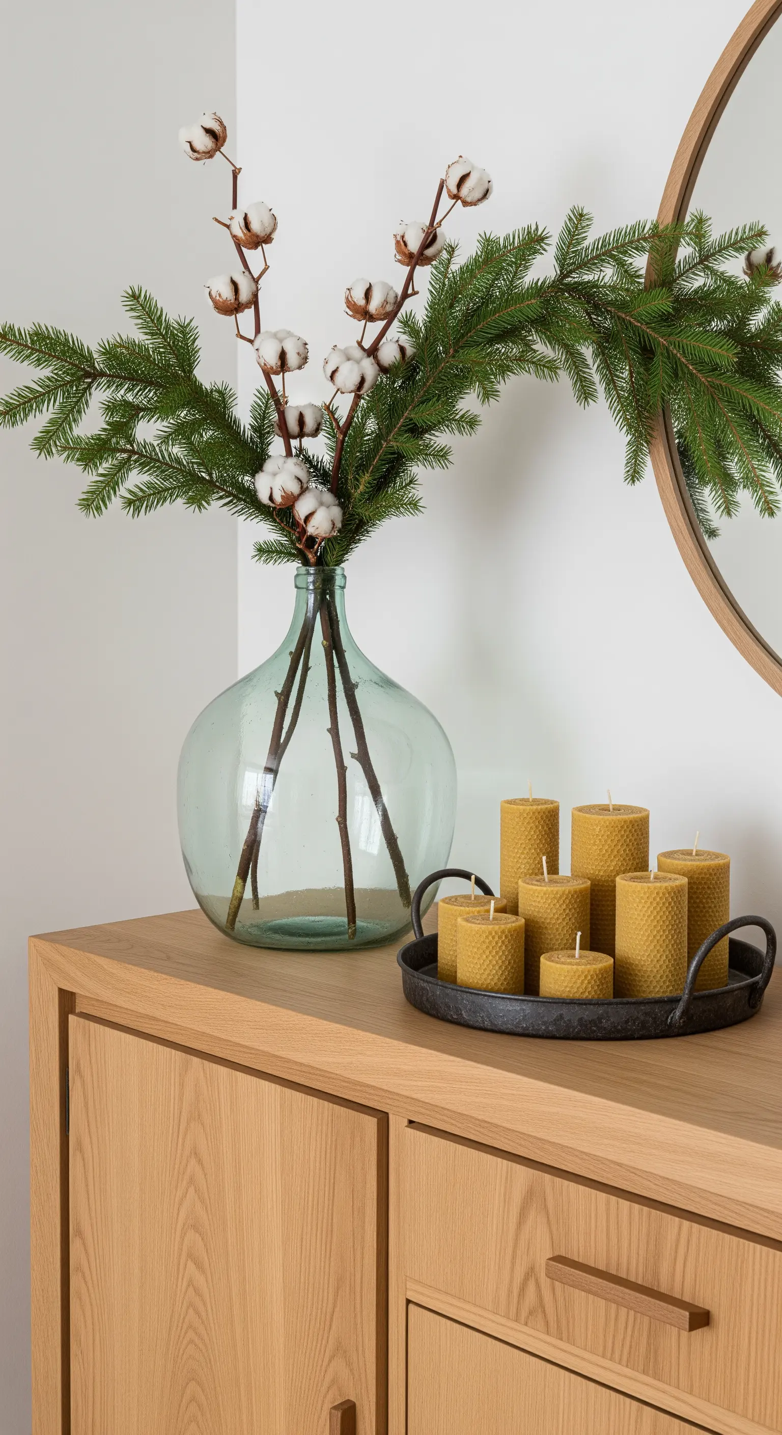 Weihnachtsdeko mit Baumwollzweigen, Tannengrün und Bienenwachskerzen.