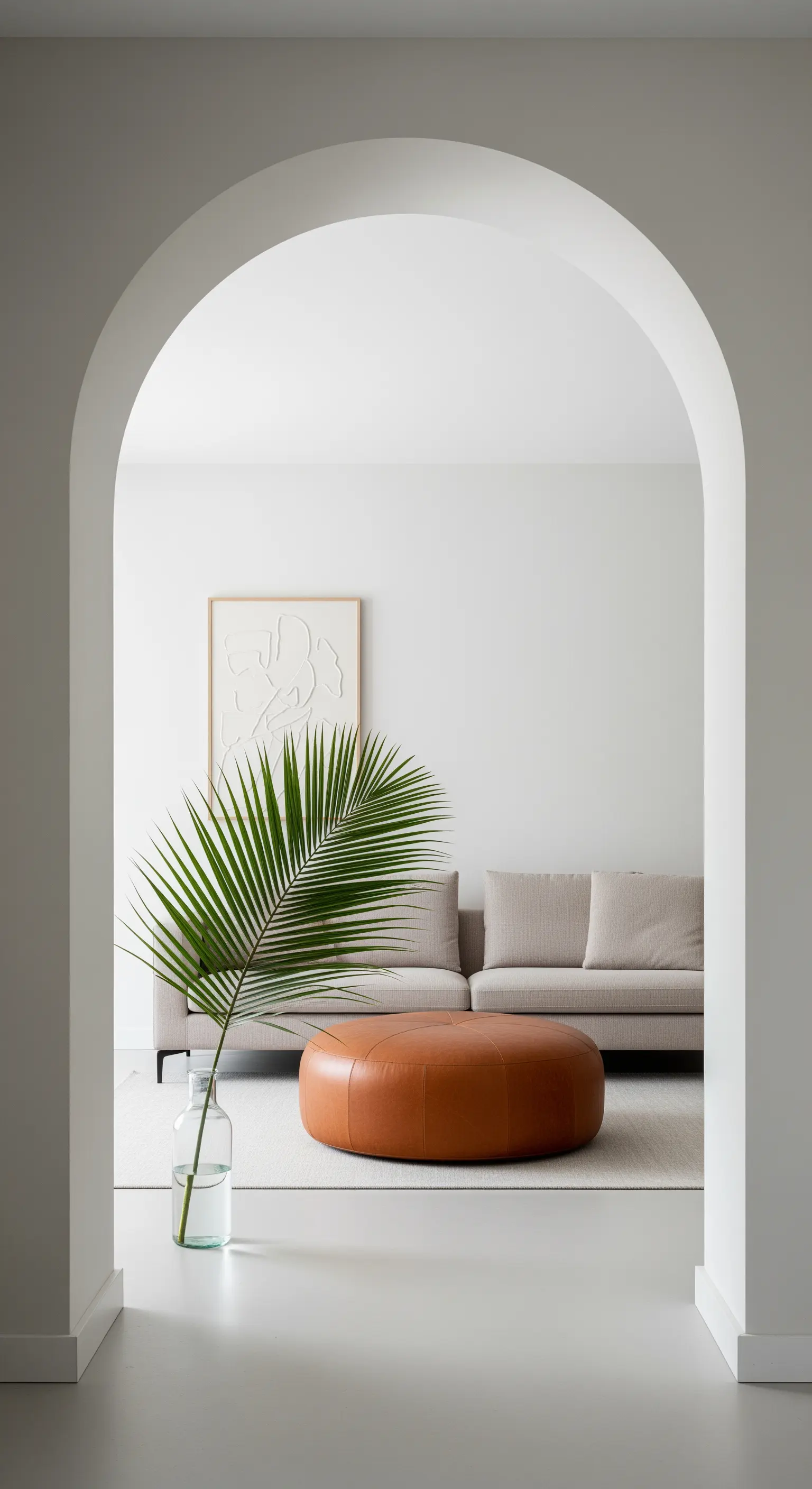 Blick durch einen Torbogen auf einen runden Lederhocker und ein beiges Sofa