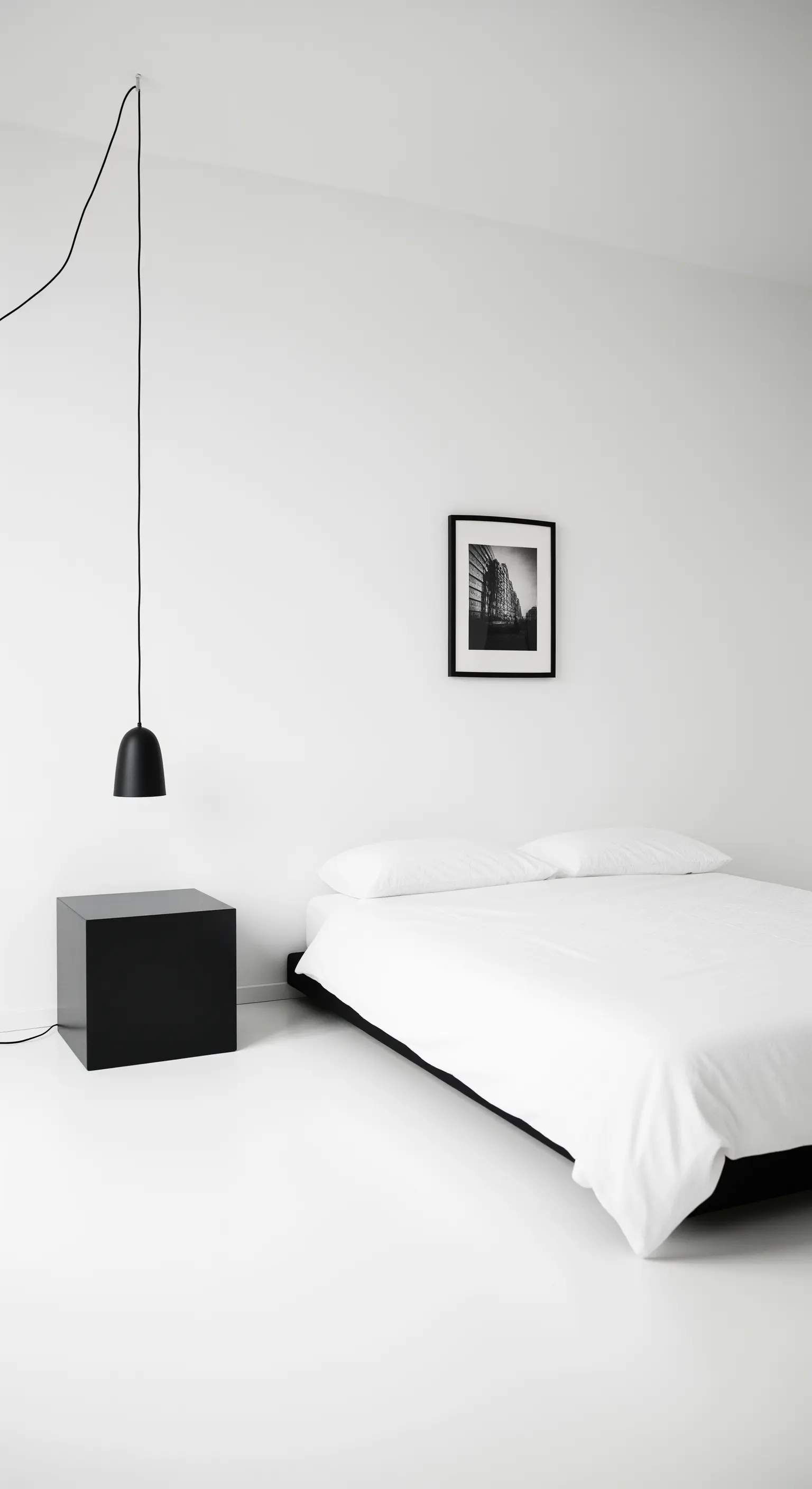 Radikal minimalistisches Schlafzimmer mit schwarzem Kubus als Nachttisch.
