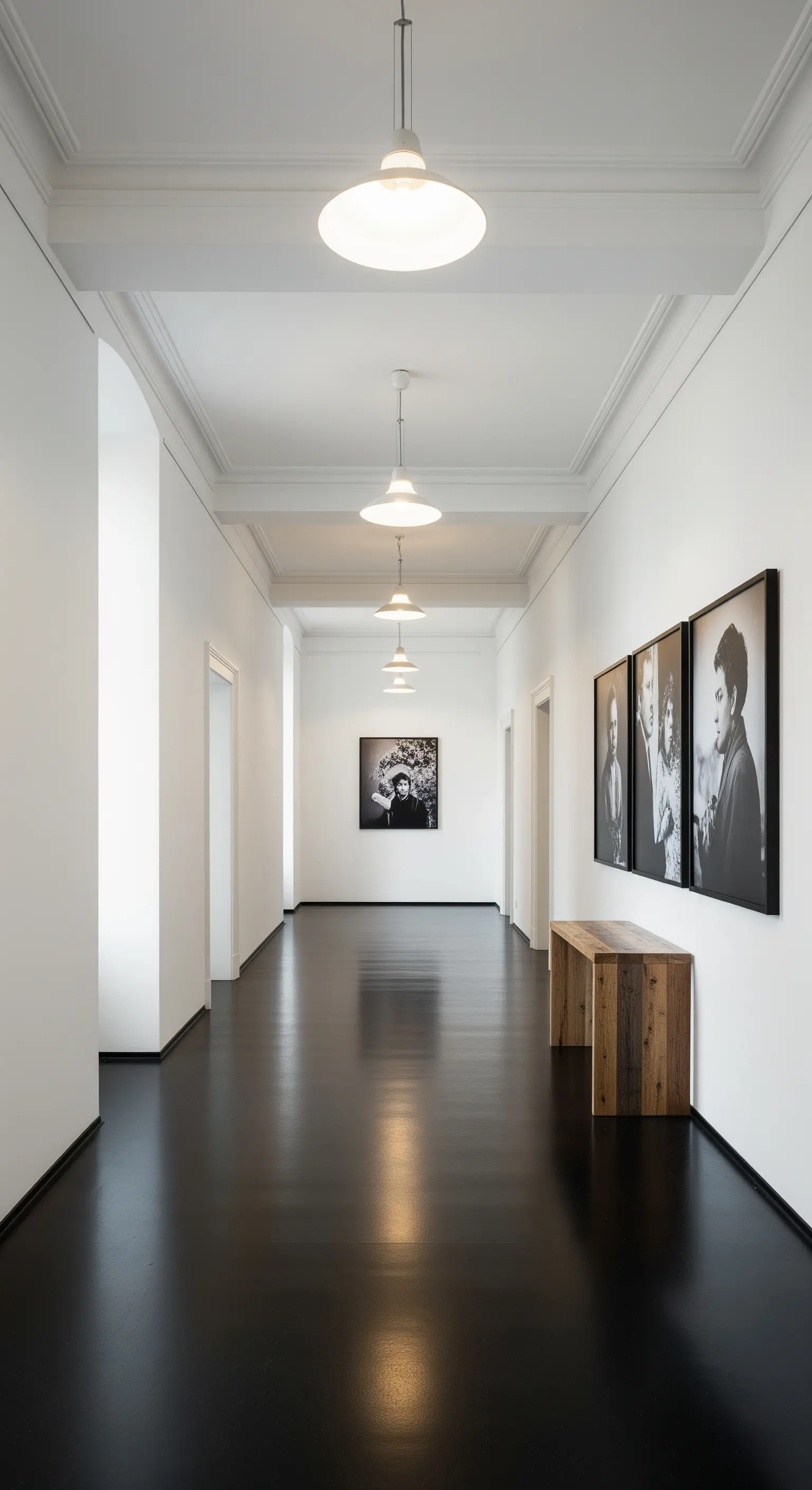 Langer, minimalistischer Flur mit dunklem Boden und Schwarz-Weiß-Fotografien an der Wand.